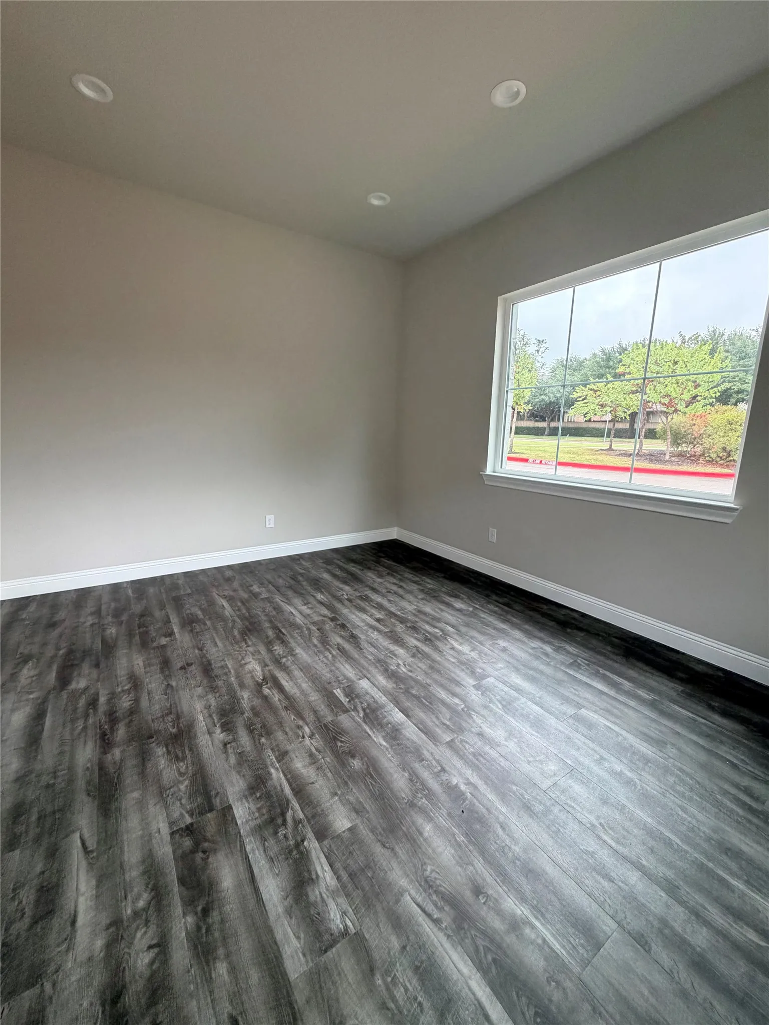 Wood-finish flooring, recessed lighting, and a large window with white trim