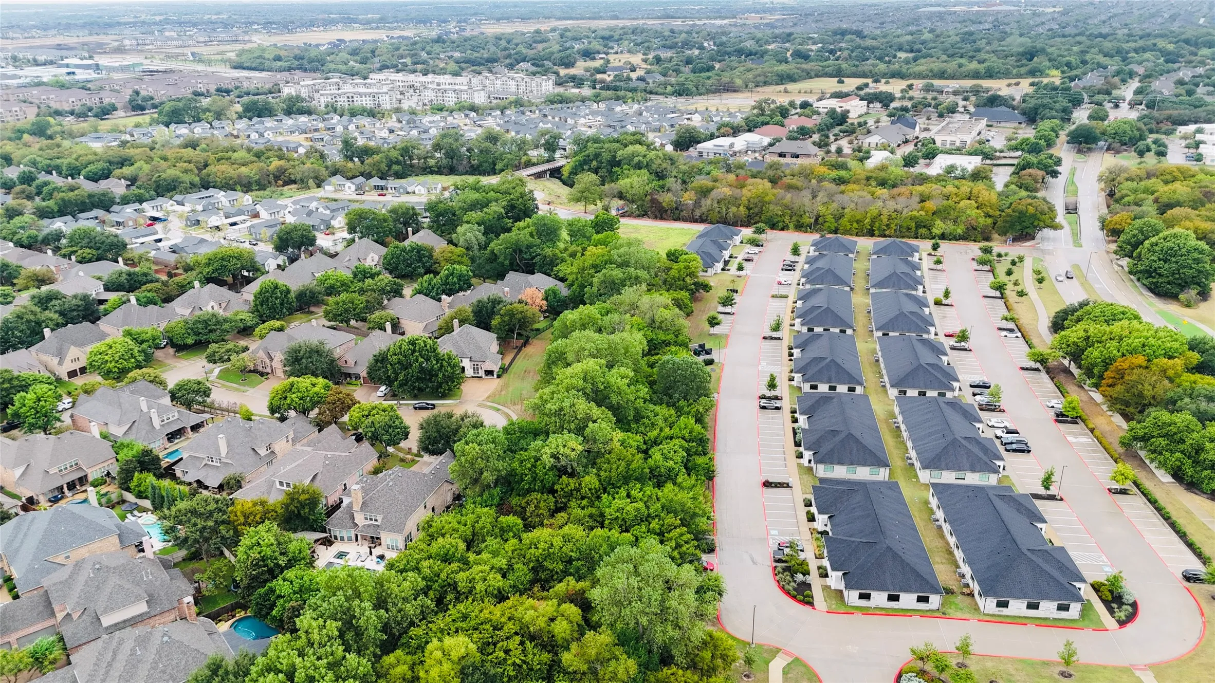 Aerial view showcasing a residential community featuring tree-lined streets, established landscaping with mature greenery, and organized residential architecture nestled within a developed neighborhood setting