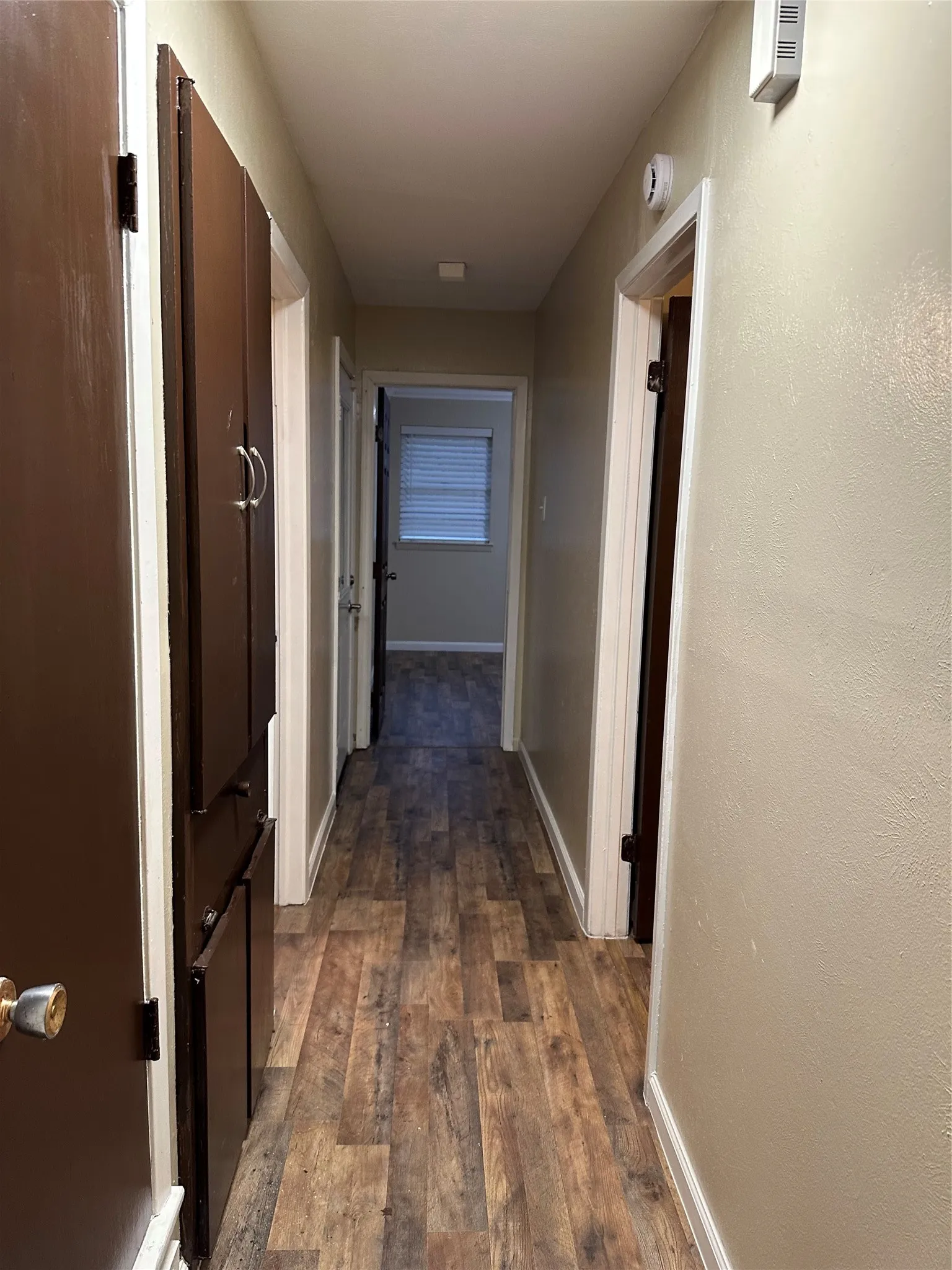 Hallway featuring wood-finish flooring, built-in cabinetry, and neutral wall tones