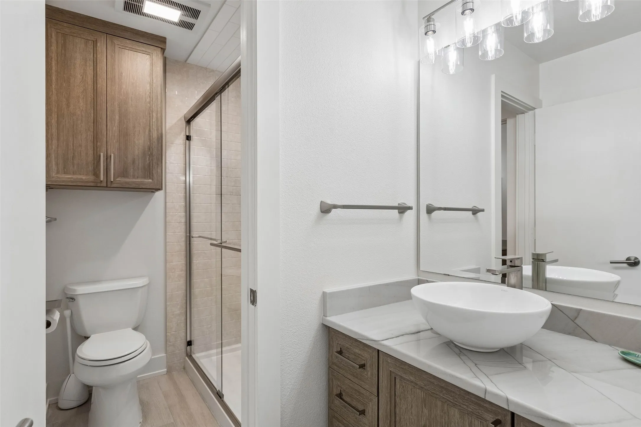 Updated Secondary Bath Shared Between Bedrooms 2 and 3 — A vessel sink, stone-look counter, updated cabinetry, and glass-enclosed shower give this bath a clean, coordinated finish.