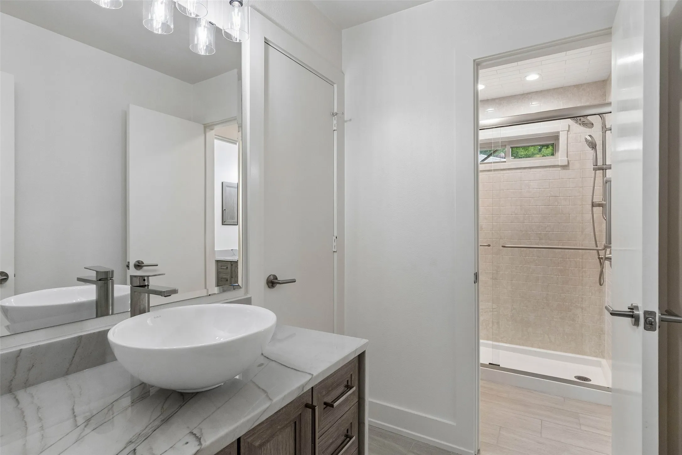 Oversized Walk-In Shower — The remodeled primary shower features extensive tilework, built-in storage niches, a bench, handheld shower fixture, and grab bars for added convenience.