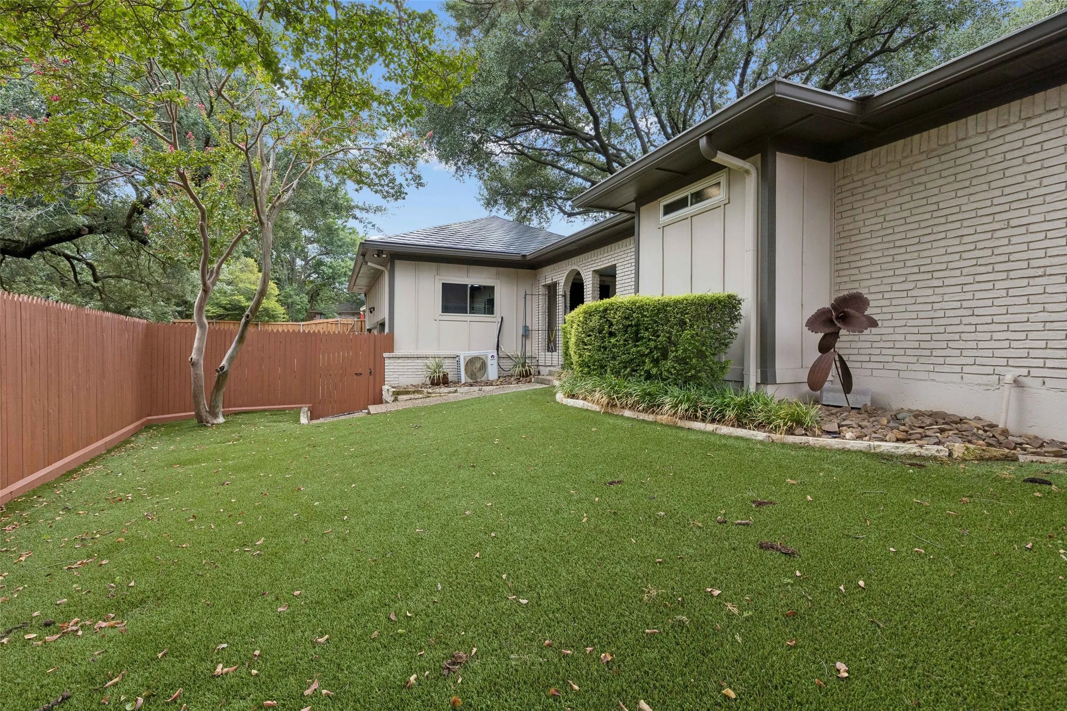 Low-Maintenance Turf Backyard — The expansive turf lawn provides a clean, green outdoor area with less upkeep, framed by mature trees and privacy fencing.