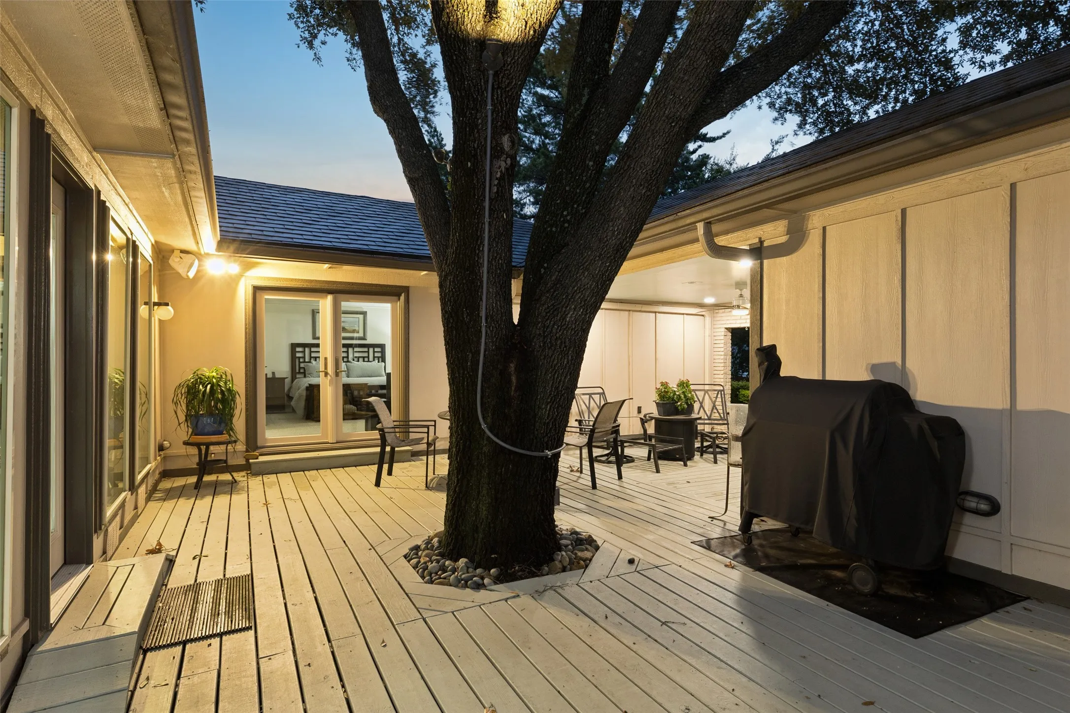 Courtyard Ambiance After Dark — Evening lighting highlights the courtyard’s mature trees and multiple access points, creating a warm setting for unwinding outdoors after sunset.