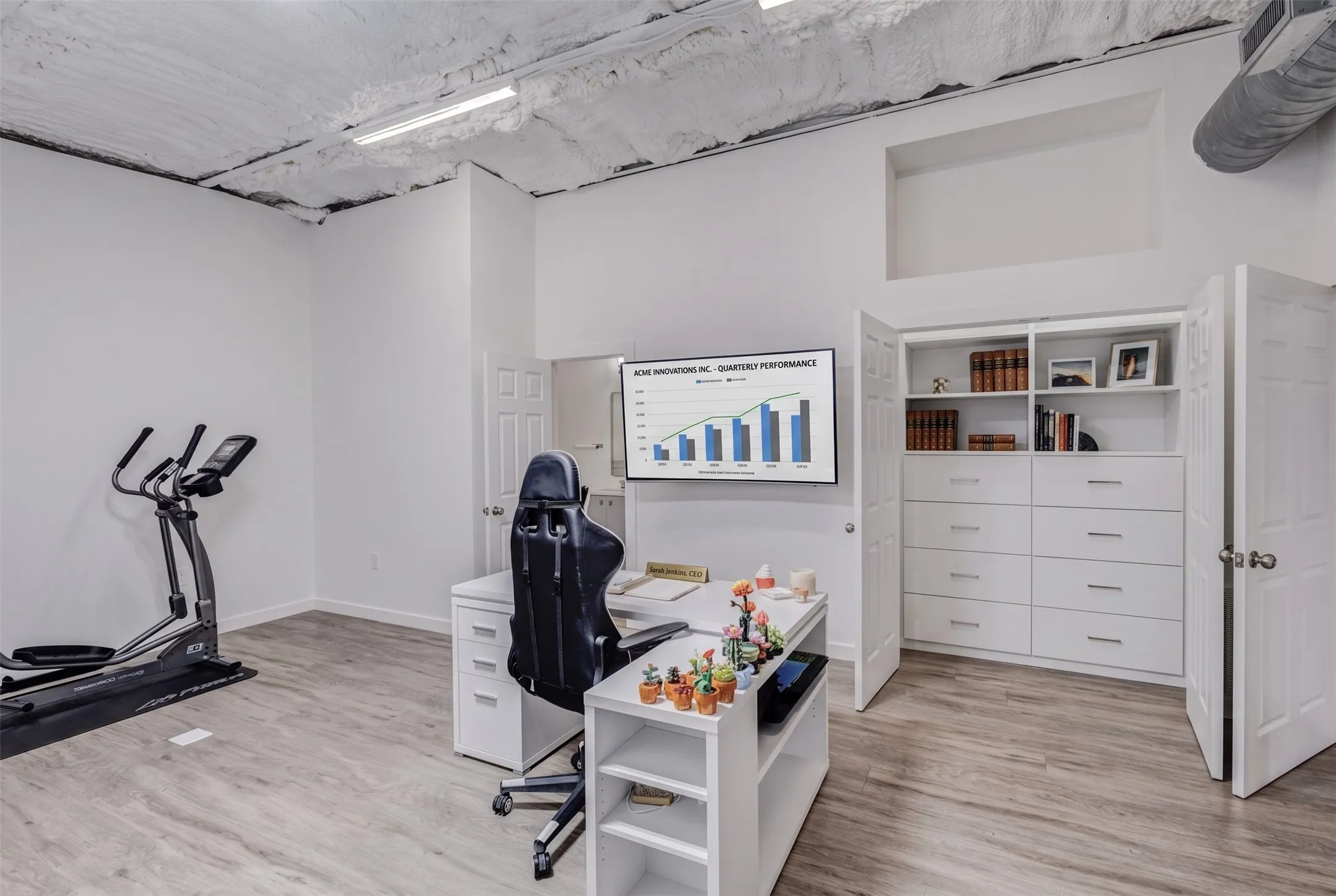 Light wood-finish flooring, white walls, exposed ceiling, built-in shelving, and white cabinetry with drawers
