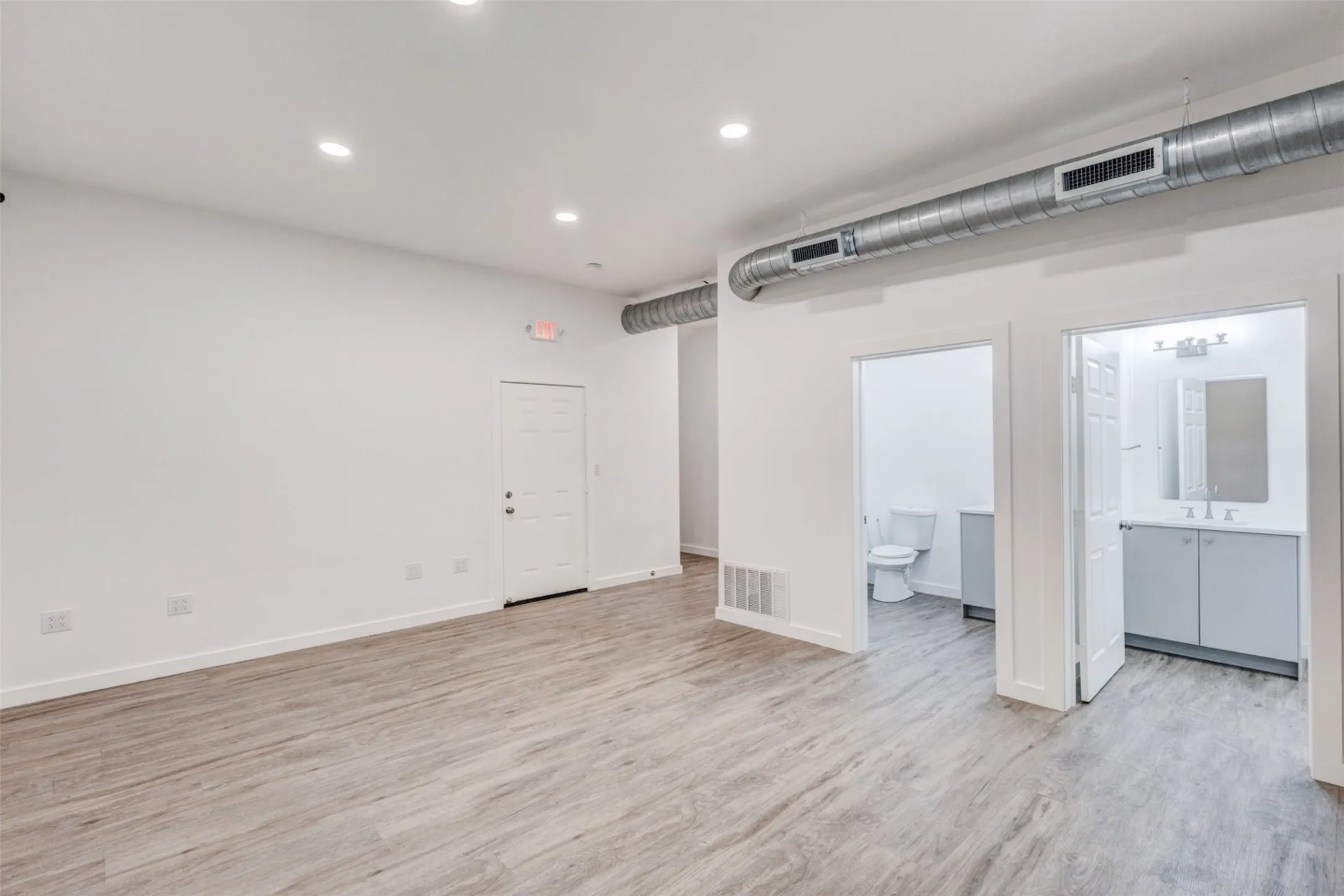 Recessed lighting, wood-finish flooring, exposed ductwork, and a bathroom with a vanity sink