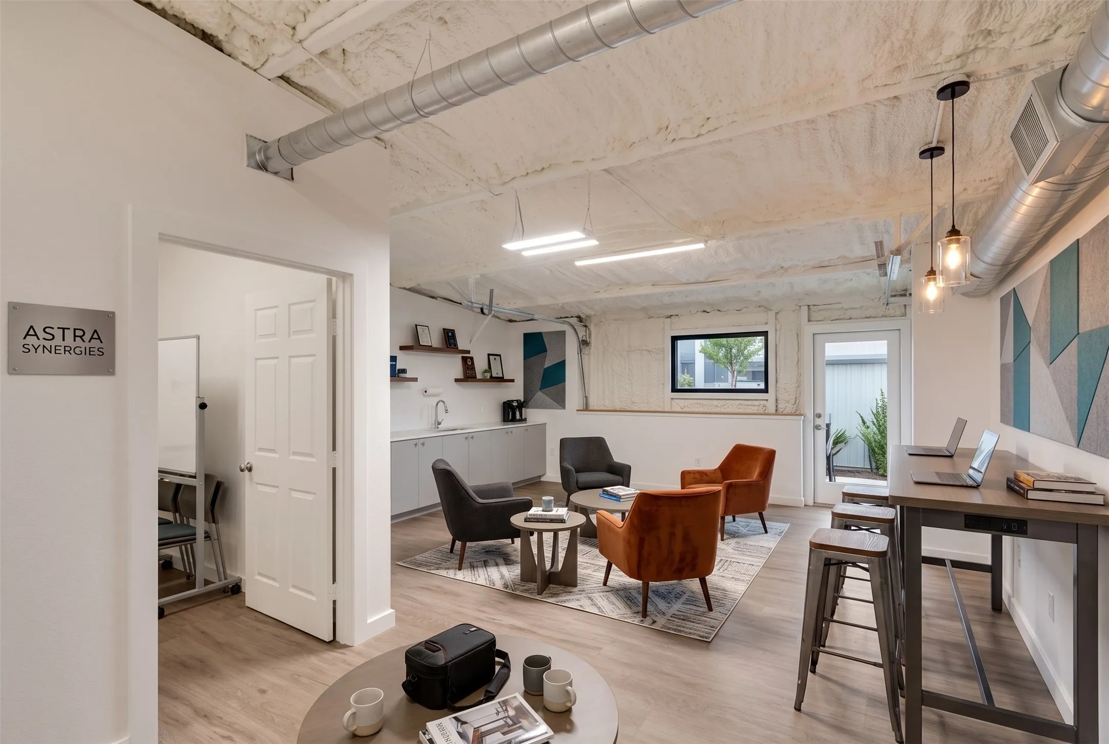 Modern office space featuring wood-finish flooring, exposed ductwork, and built-in task lighting