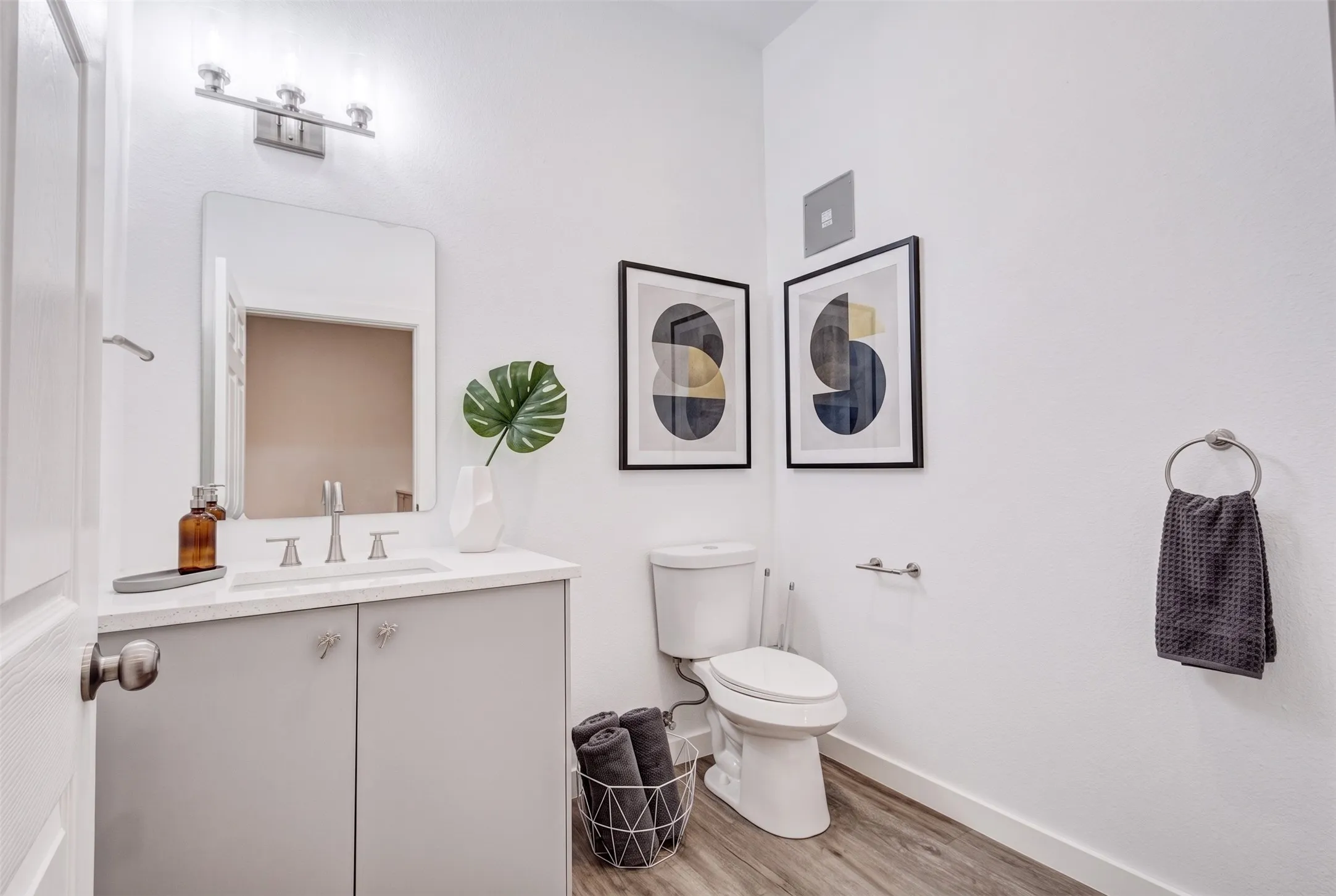 White vanity with a light-toned countertop, a rectangular mirror, and a three-light vanity fixture - AI Generated