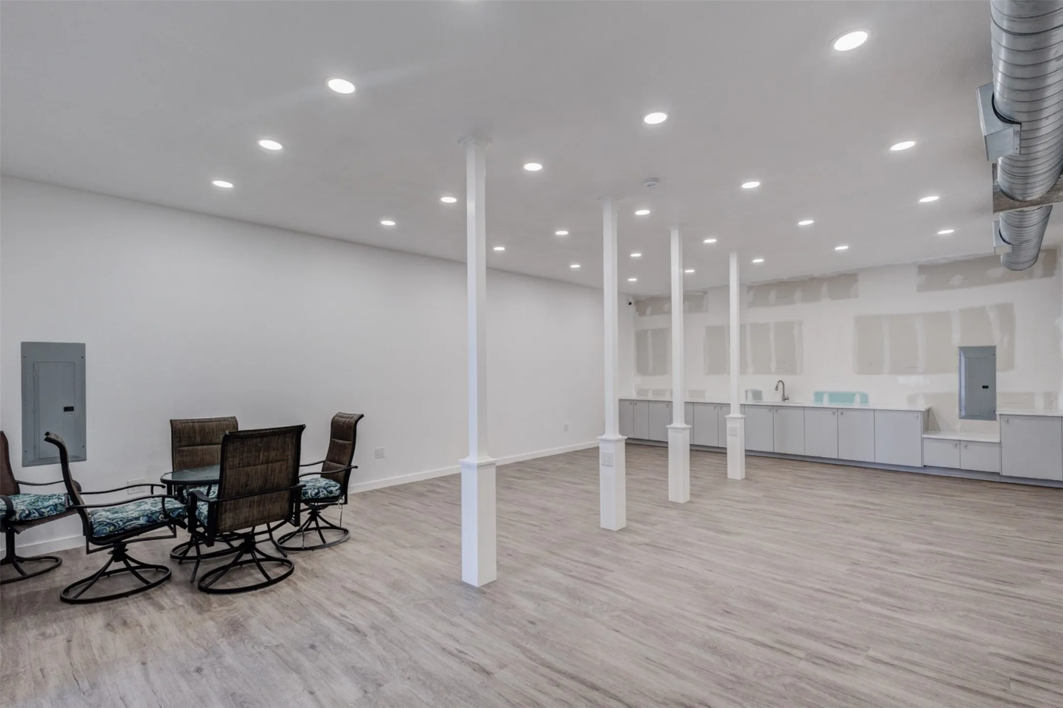 Expansive lower level with recessed lighting, wood-finish flooring, exposed ductwork, and built-in cabinetry with a sink
