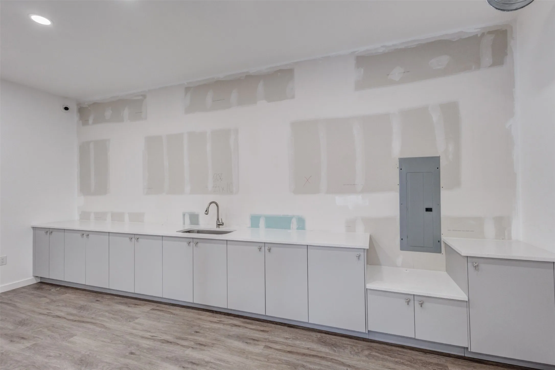 Wood-finish flooring, recessed lighting, and extensive cabinetry with integrated sink