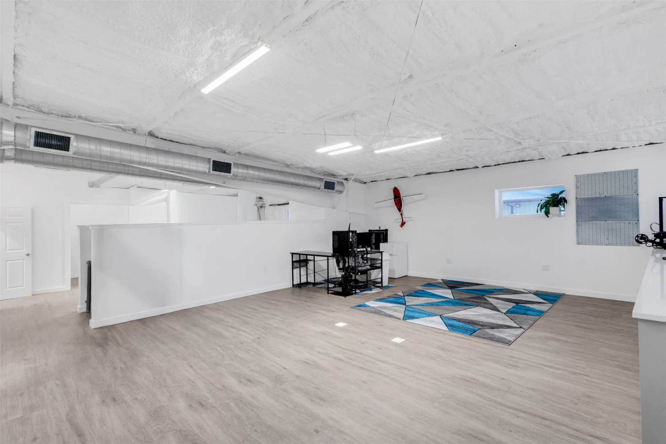 Spacious interior with wood-finish flooring, white walls, and exposed ductwork
