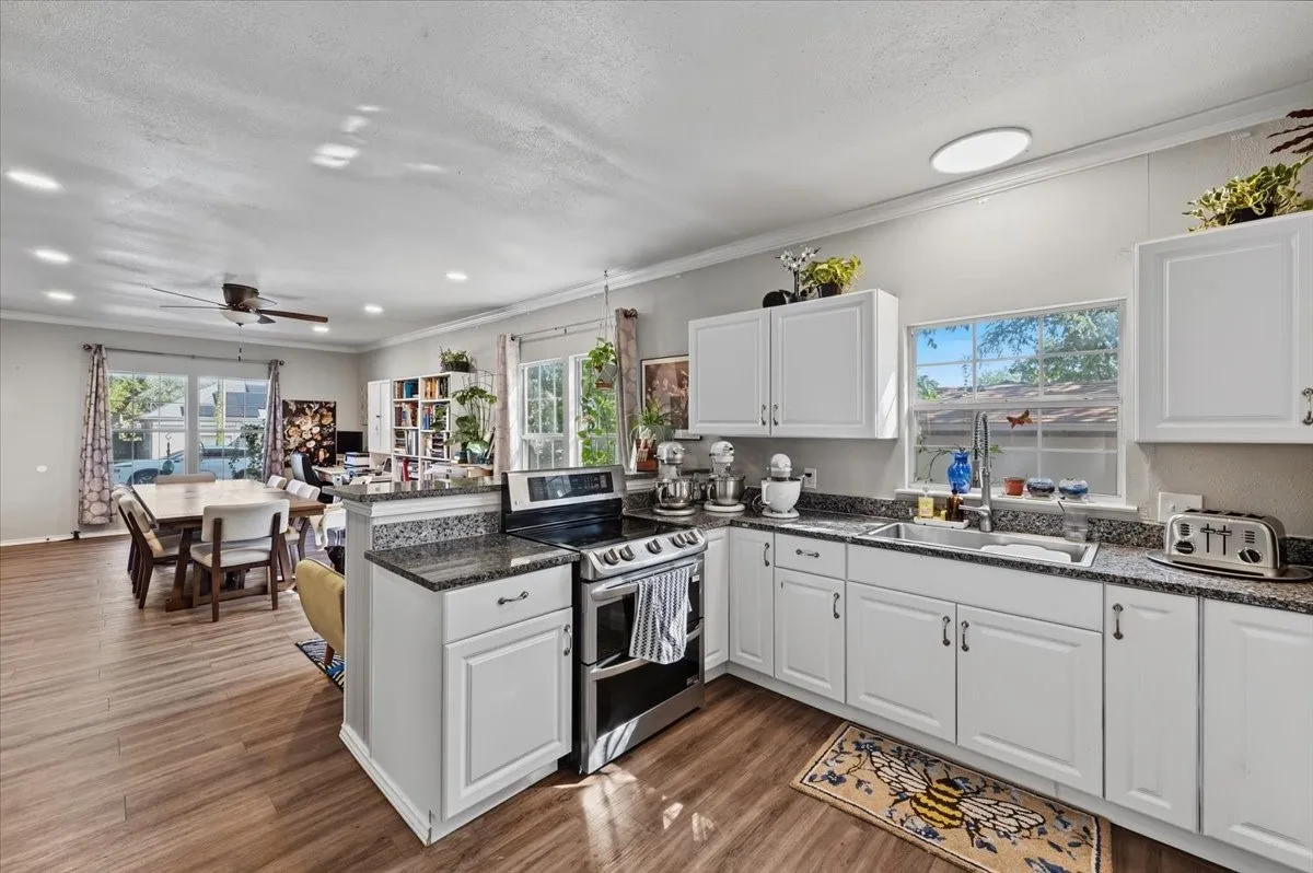 White cabinetry with dark countertops, stainless steel appliances, and wood-finish flooring