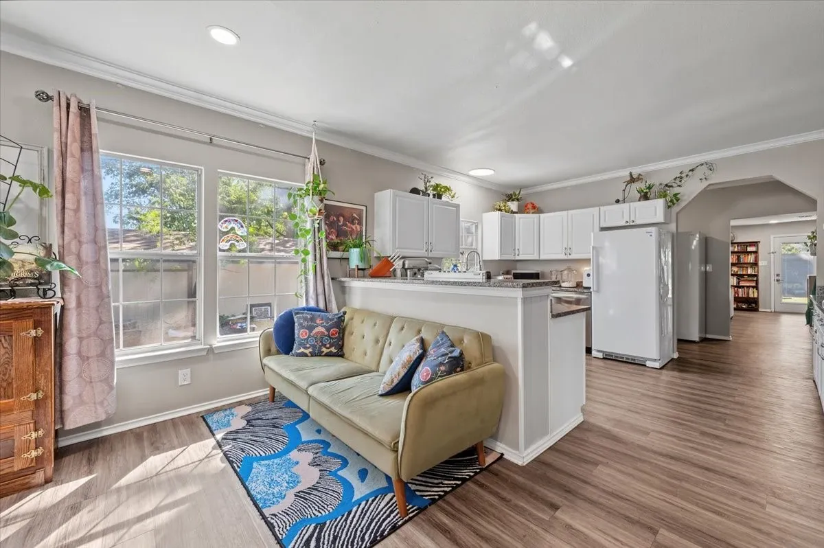 Open-concept living area with wood-finish flooring, recessed lighting, and crown molding
