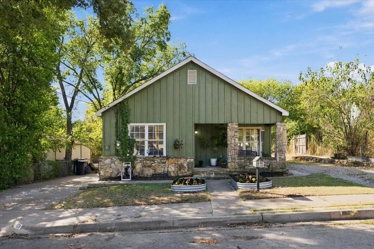 Gable roofline, board and batten siding, stone facade accents, covered entry, and a paved driveway