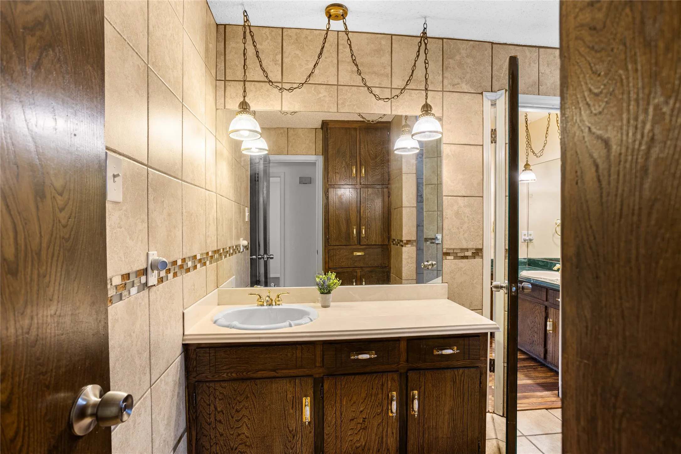 Wood-finish vanity with a recessed sink and single-handle faucet, complemented by a large wall-mounted mirror