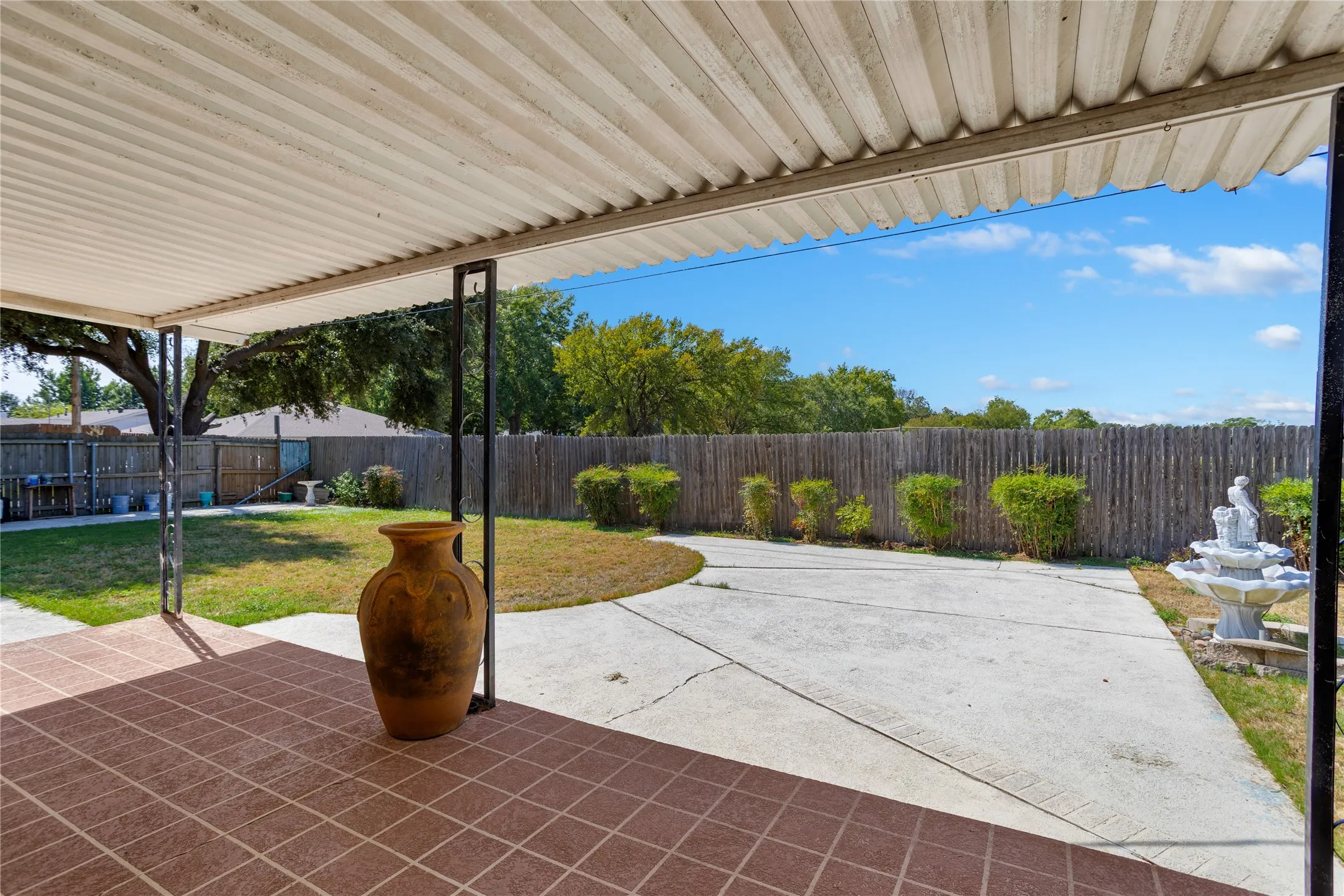 Covered patio with square terracotta-toned tile flooring, supported by dark metal posts