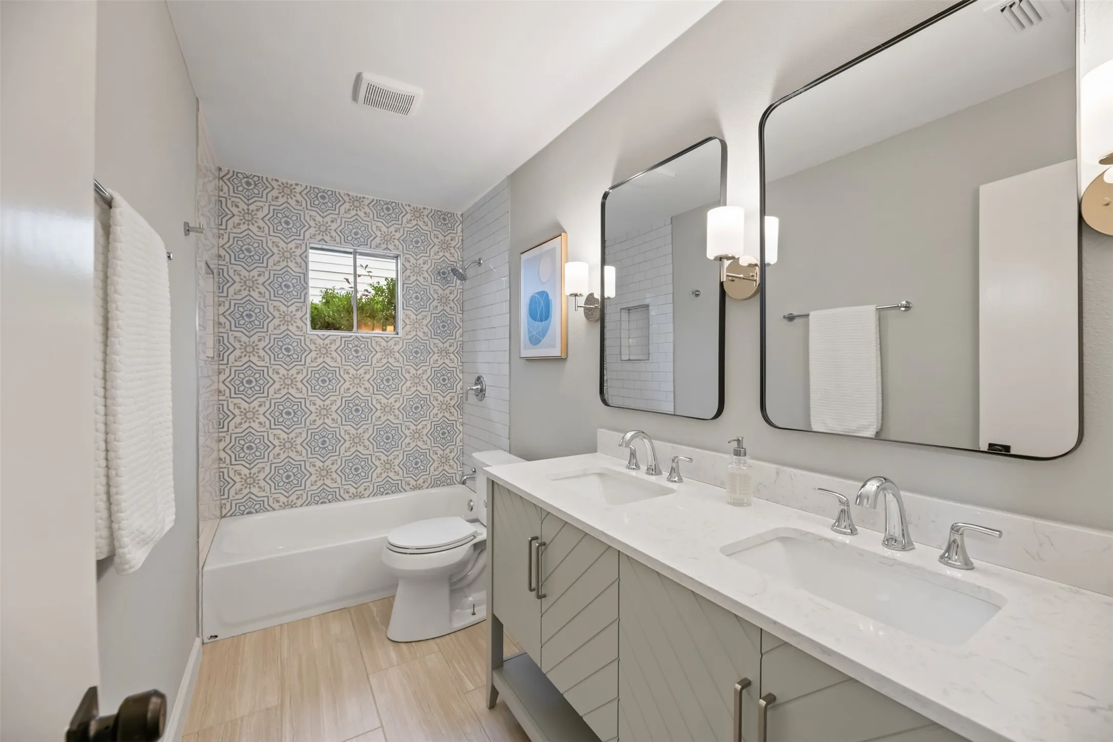 Hall bathroom with a new dual sink vanity, faucets, bathtub, and tile surround