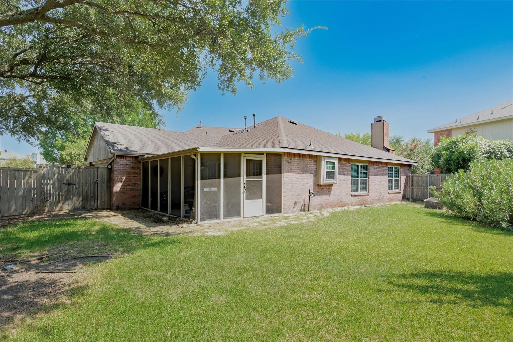 Expansive backyard featuring a screened porch, brick exterior, and a wood privacy fence