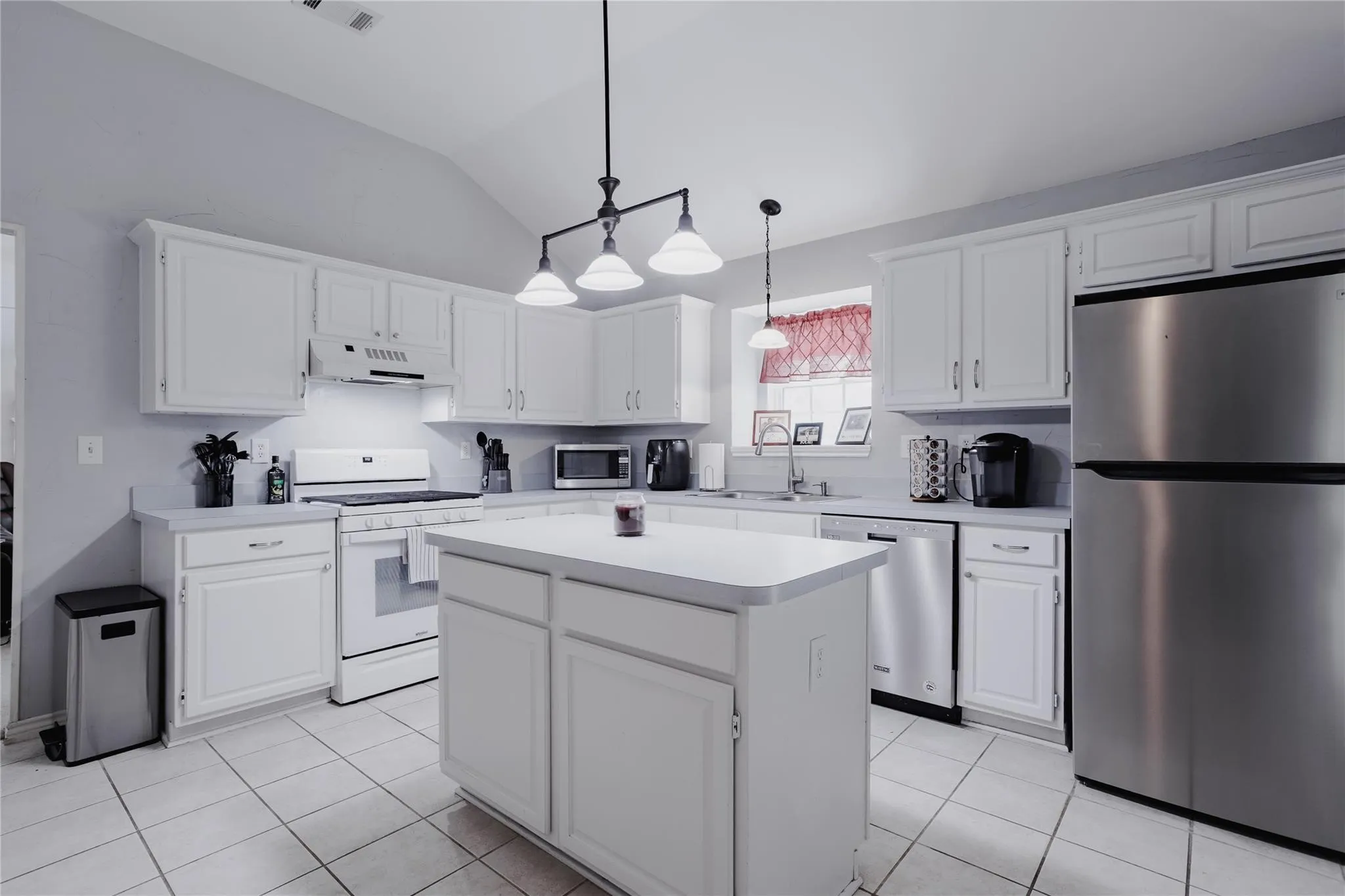 Spacious kitchen featuring white cabinetry, light-toned countertops, and a central island