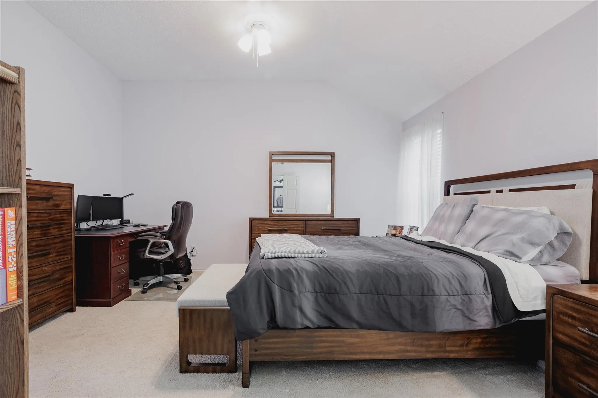 Vaulted ceiling with a flush-mount ceiling light fixture, wall-to-wall carpeting, and a window with blinds and sheer curtains