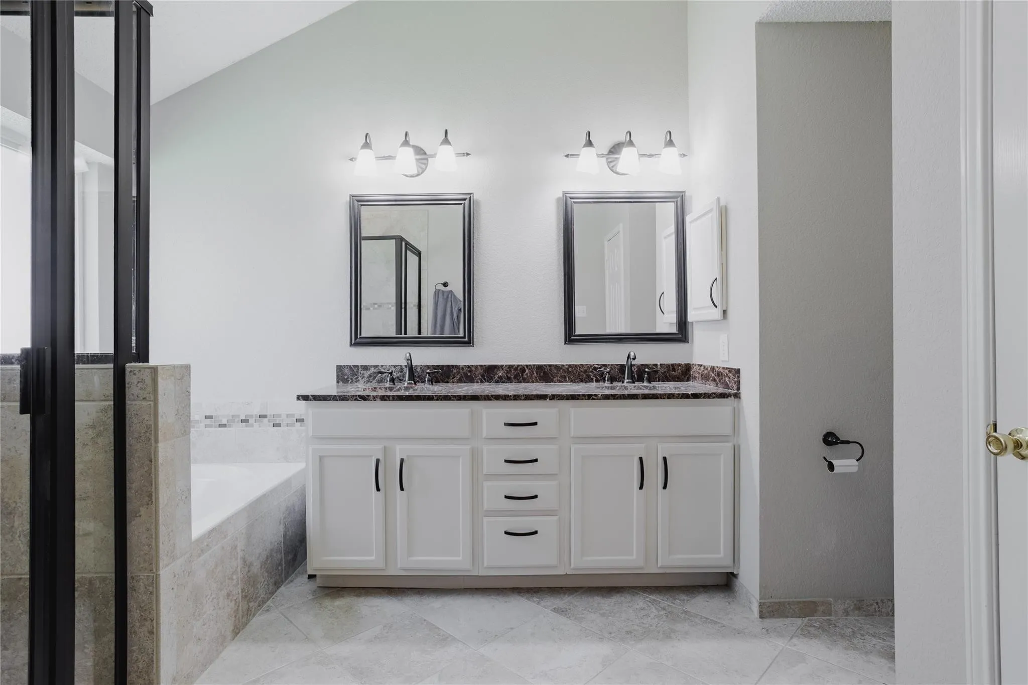 Dual vanity with white cabinetry and dark countertops