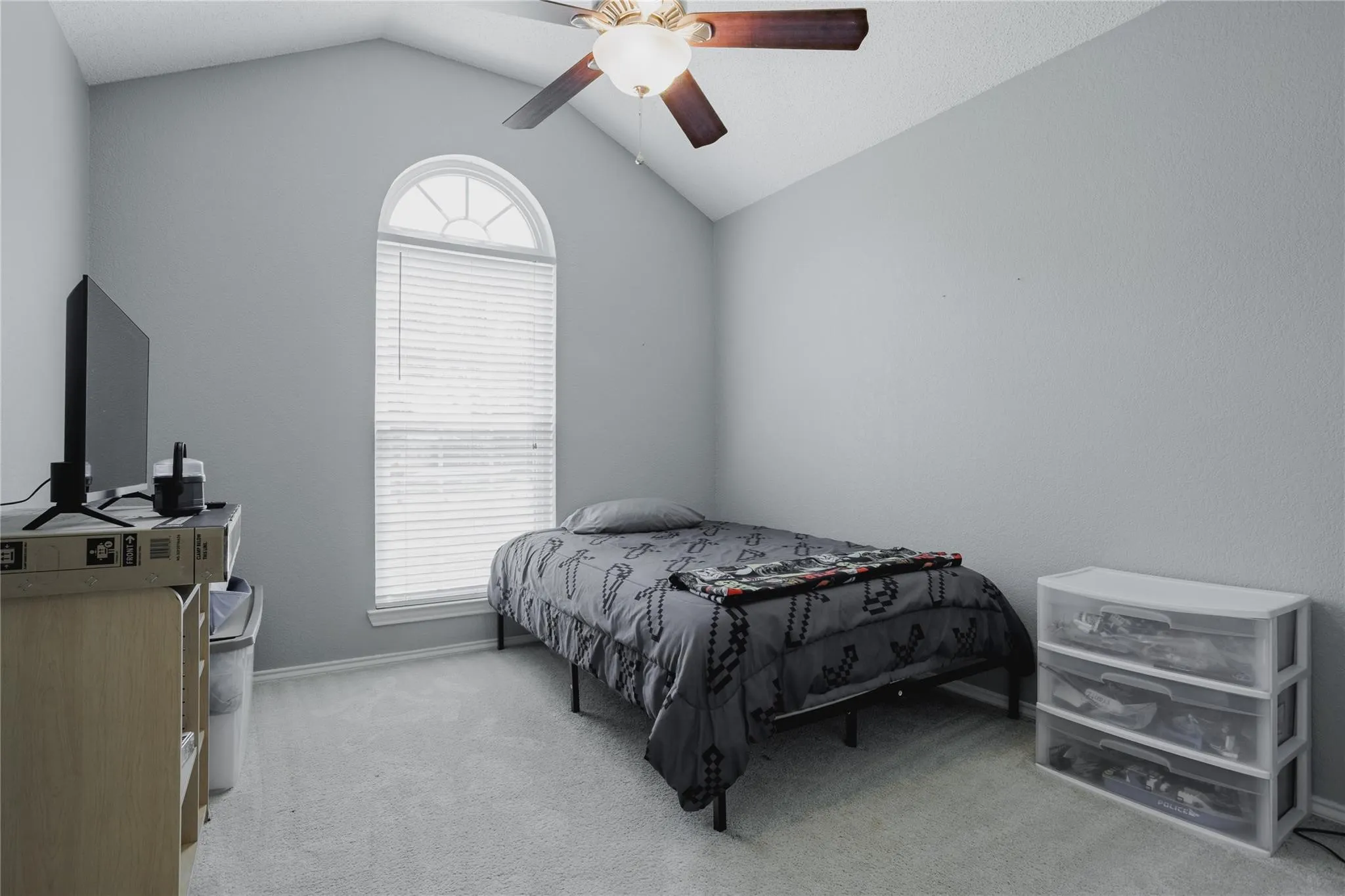 Vaulted ceiling with ceiling fan, arched window with horizontal blinds, neutral wall paint, and carpet flooring