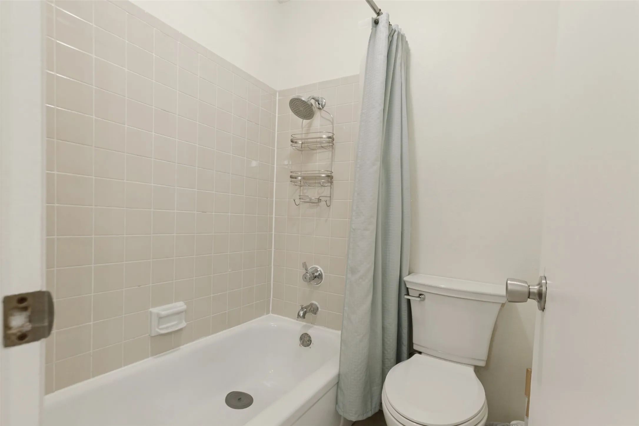 Bathroom featuring a shower/tub combination, tiled shower surround, and a toilet