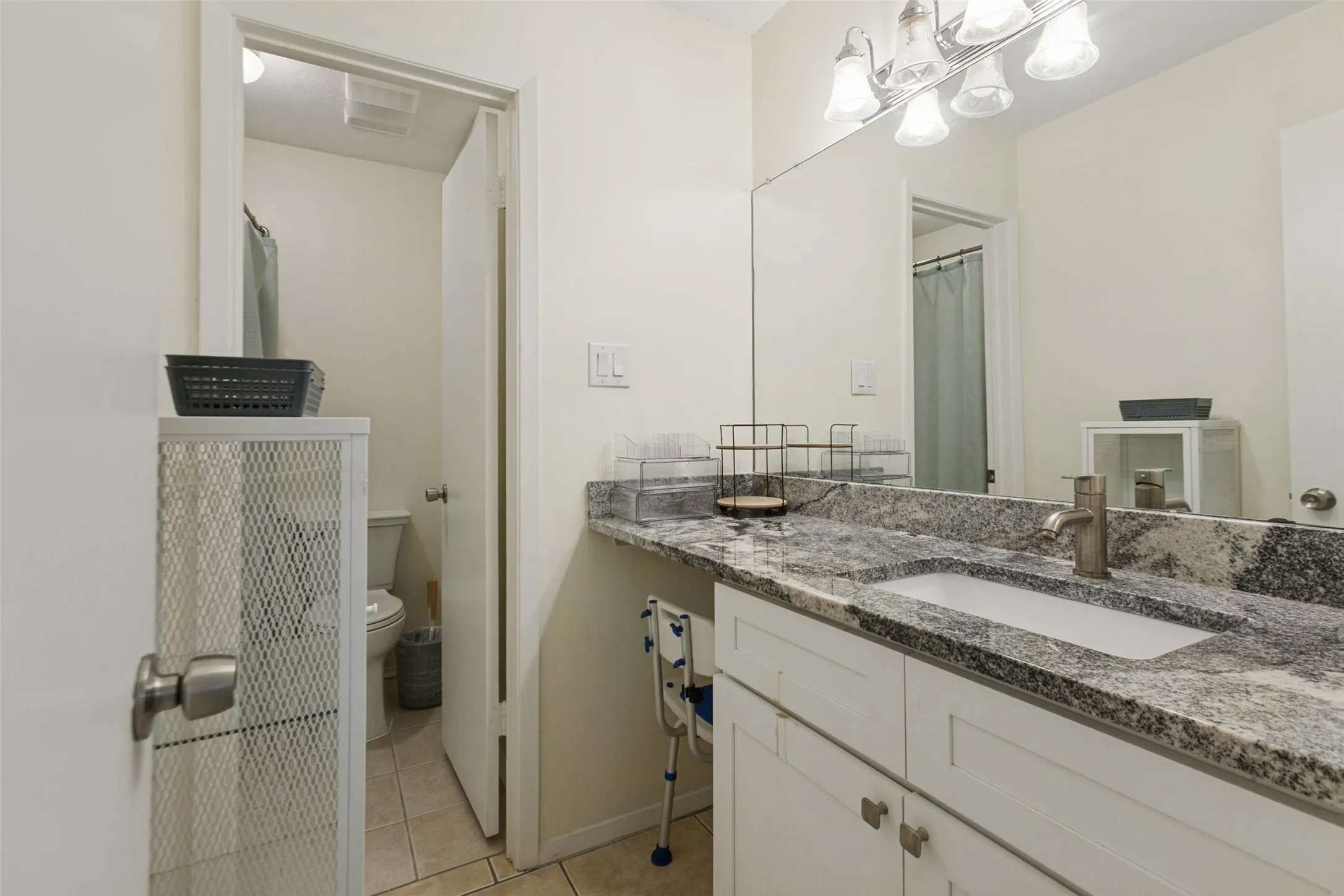 Vanity featuring a stone countertop, an undermount sink, and a brushed nickel faucet