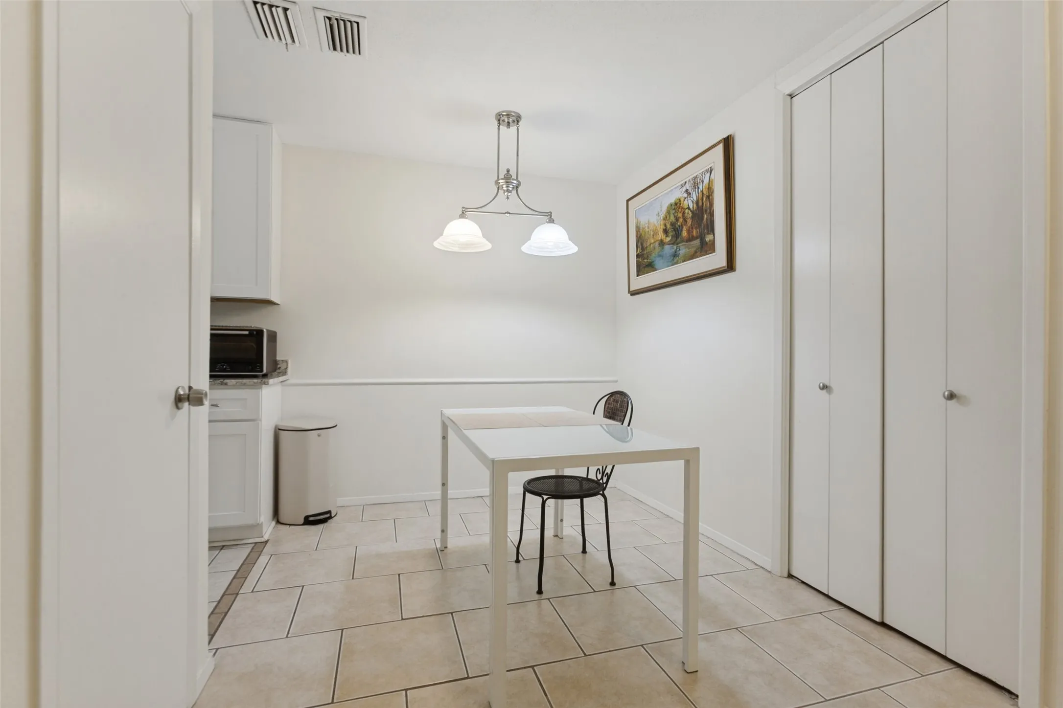 White cabinetry with a microwave, tile flooring, and a semi-flush mount light fixture