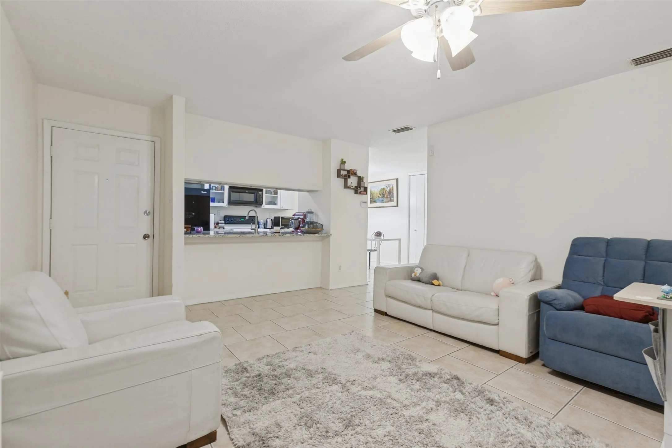 Recessed kitchen opening with a built-in breakfast bar, tile flooring, and a ceiling fan with integrated lighting