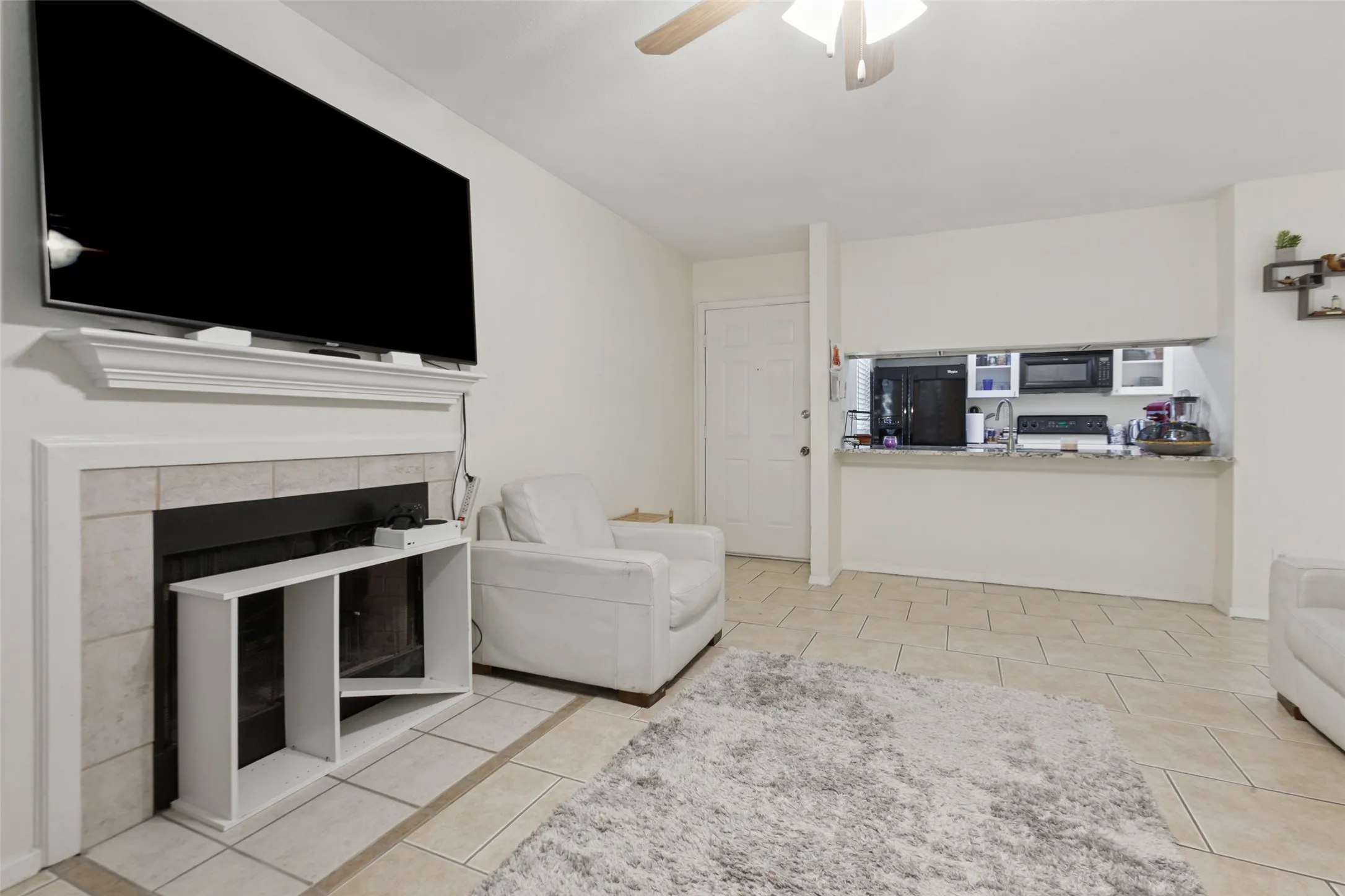 Tiled flooring throughout, a fireplace with a mantel, and a kitchen pass-through with a breakfast bar