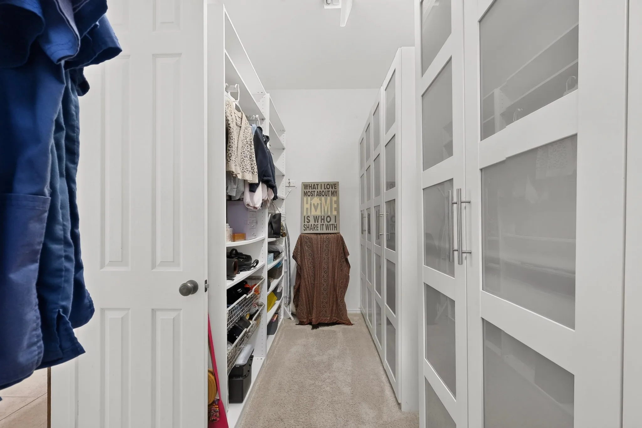 Built-in closet system with open shelving, hanging racks, and white framed doors with frosted glass panels