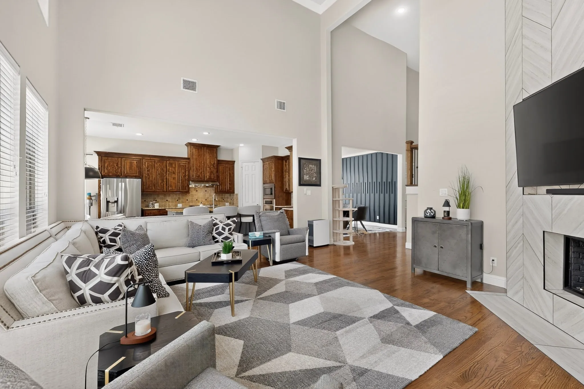 Vaulted ceilings, wood-finish flooring, a contemporary fireplace with tile surround, and built-in kitchen cabinetry with stainless steel appliances