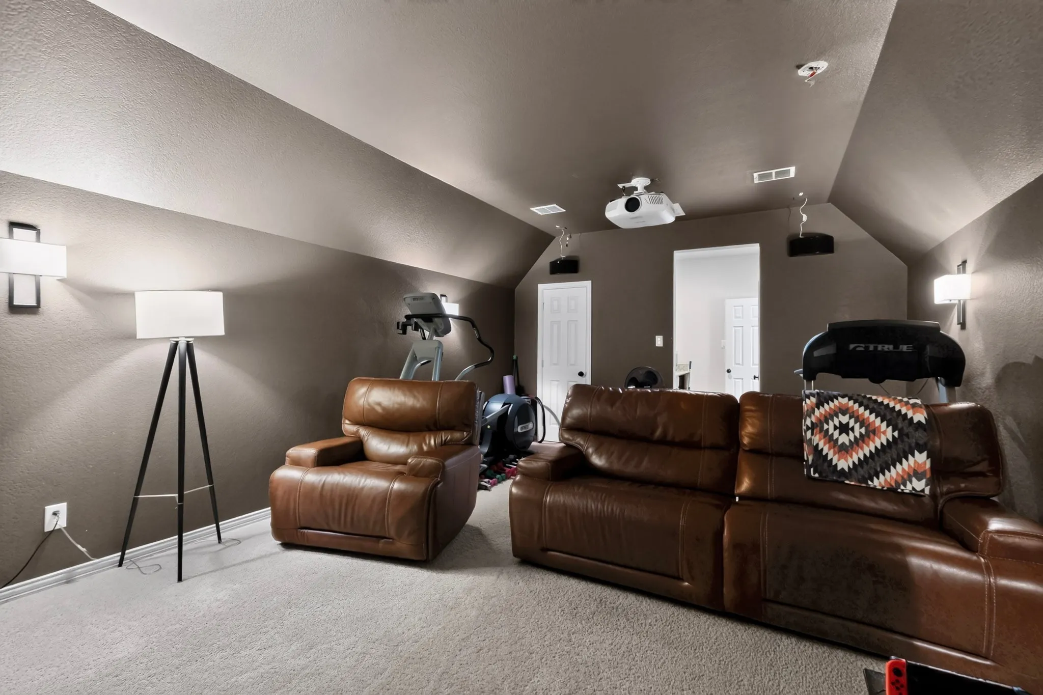 Carpeted room with sloped ceilings, recessed lighting, and wall-mounted sconces