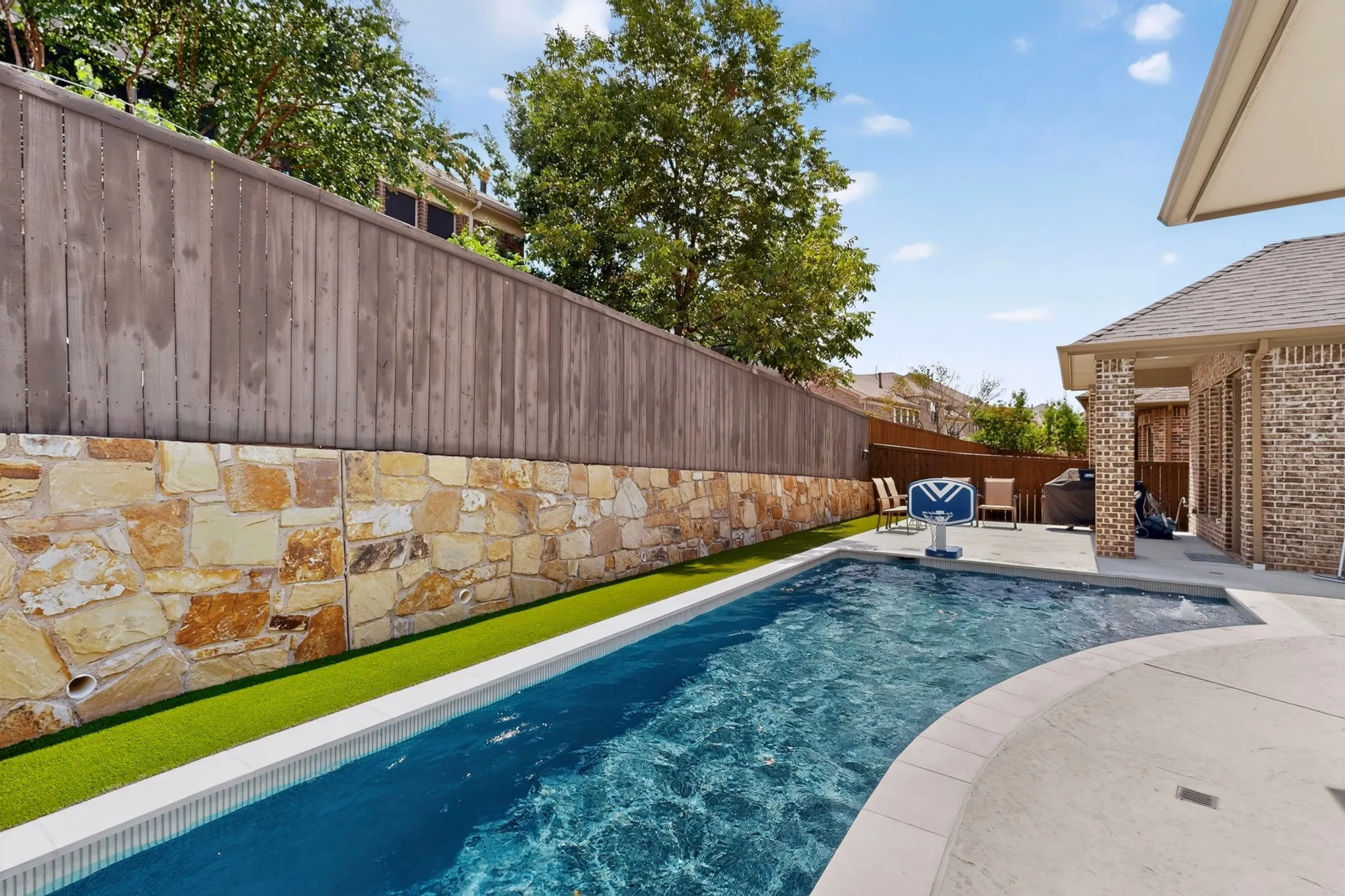 Outdoor swimming pool with integrated spa and surrounding concrete decking