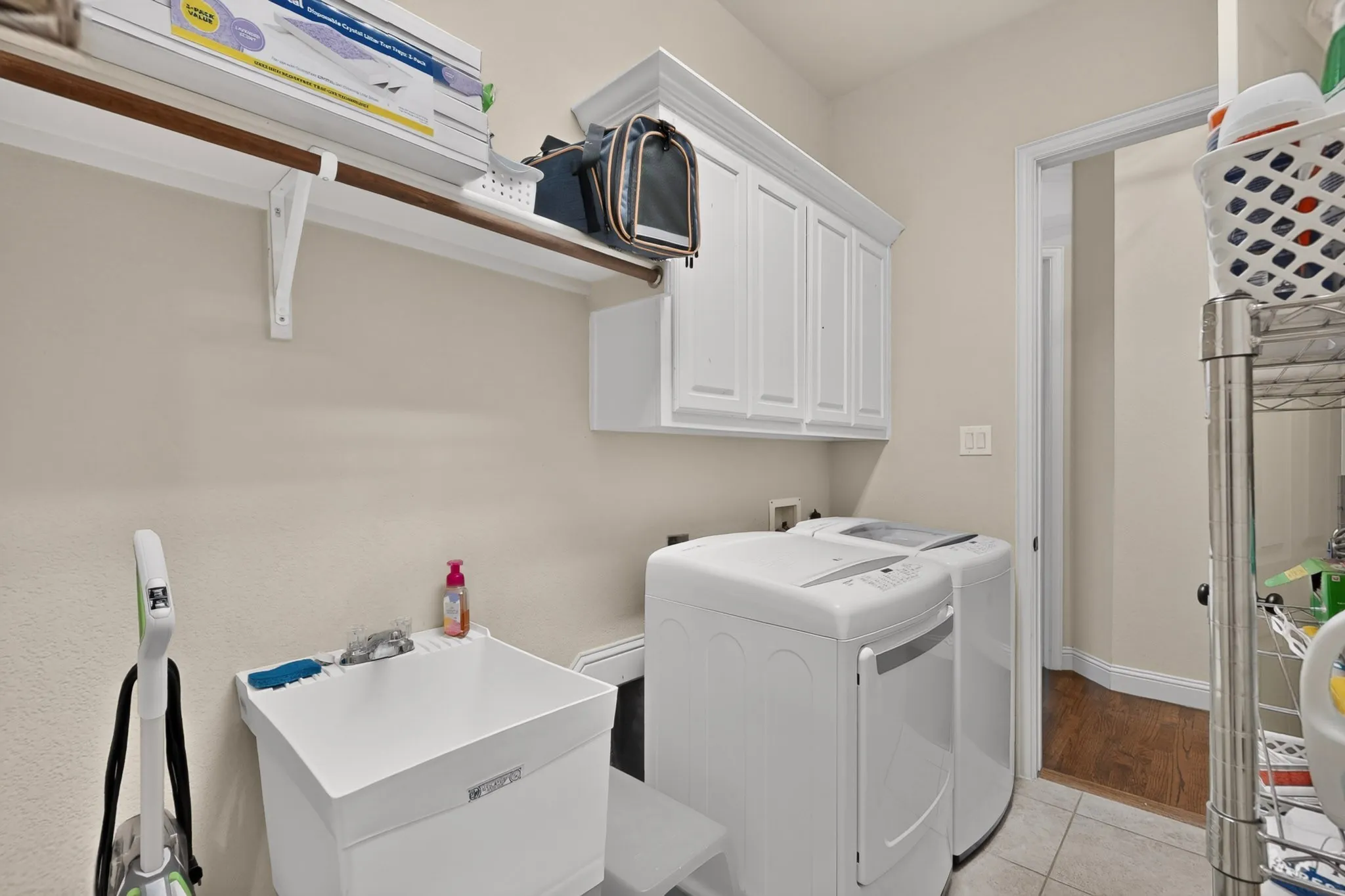 Laundry area featuring white cabinetry, a utility sink, and tile flooring