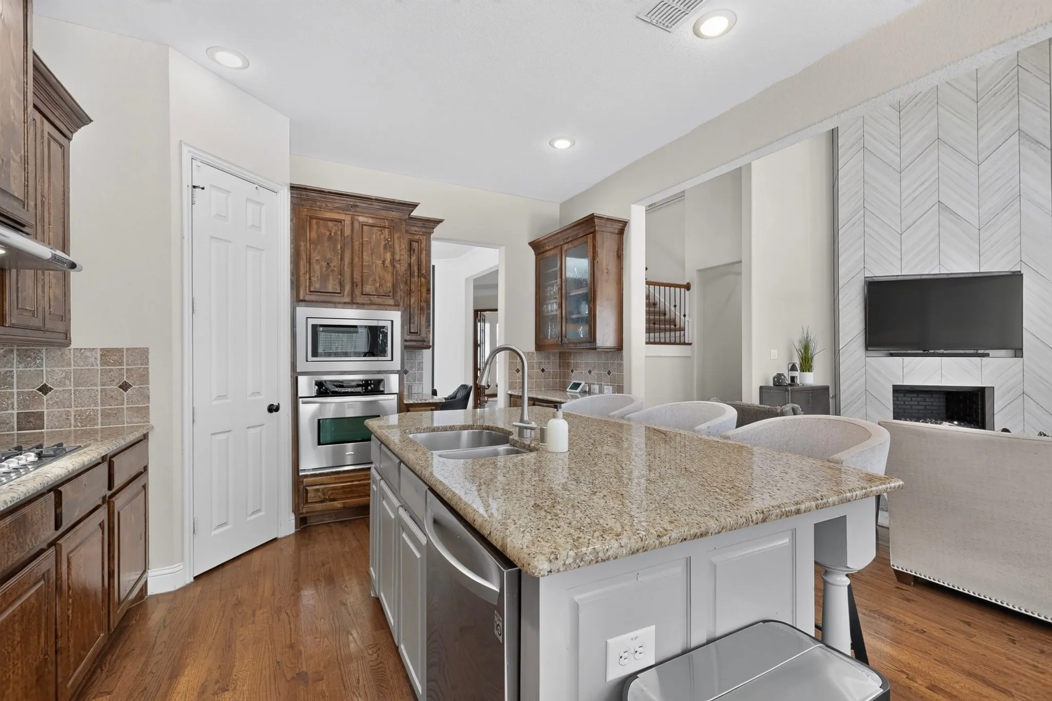 Gourmet kitchen featuring a central island with granite countertops, stainless steel sink, and integrated dishwasher