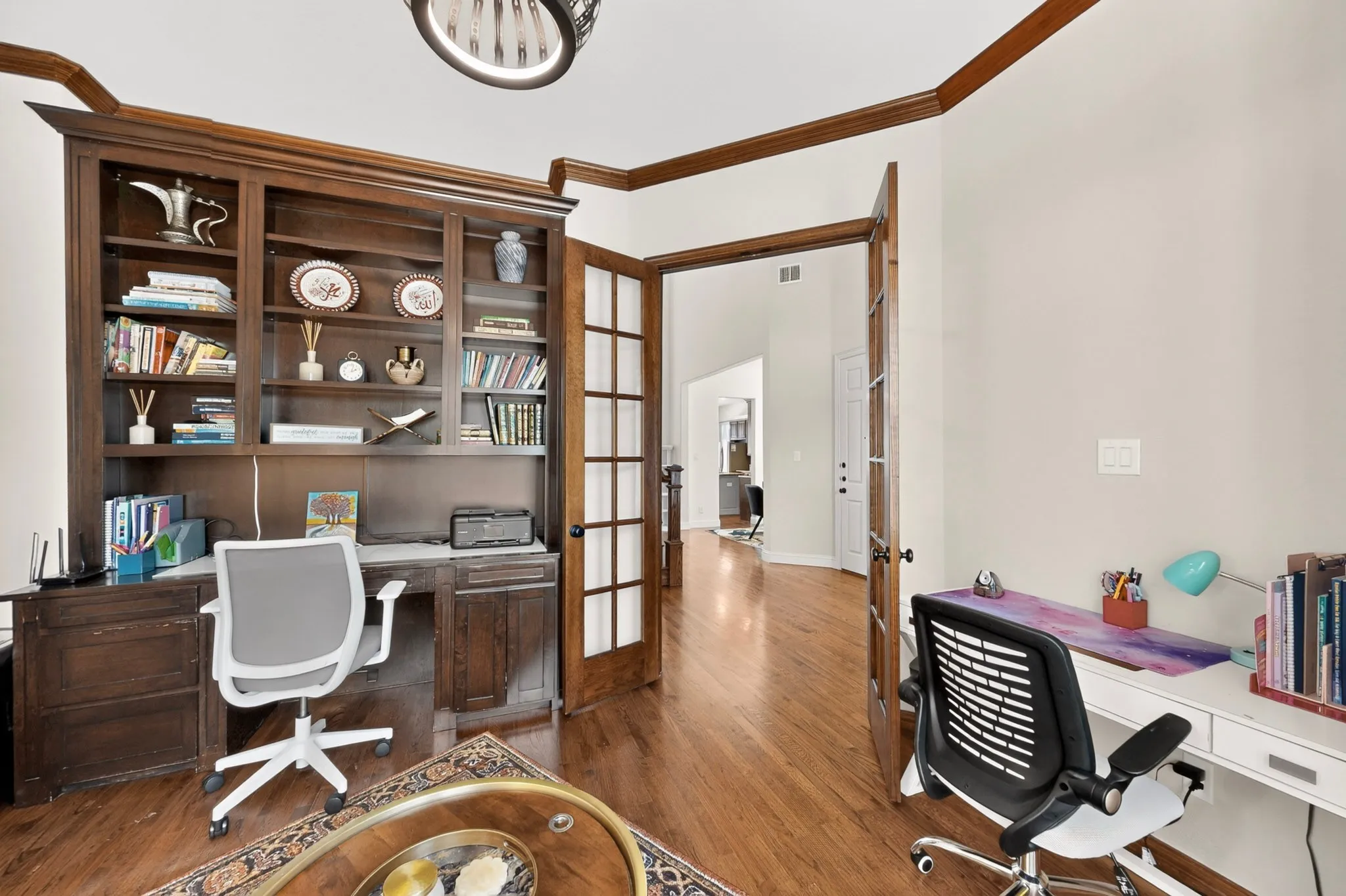 Dedicated work area featuring rich wood-finish flooring, built-in shelving, and French doors