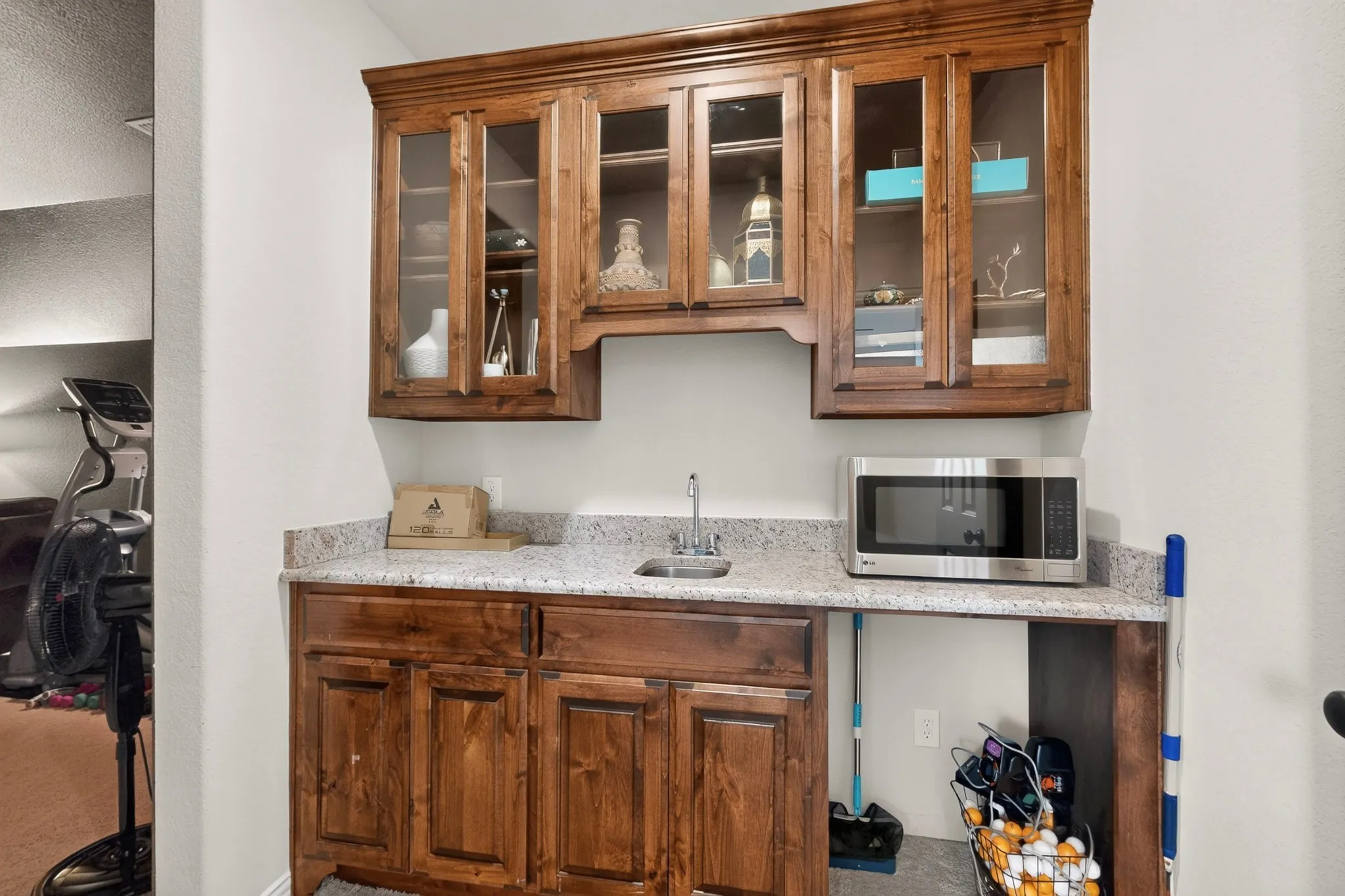 Built-in cabinetry with glass-front upper cabinets, light-toned countertop, and an integrated sink with a faucet