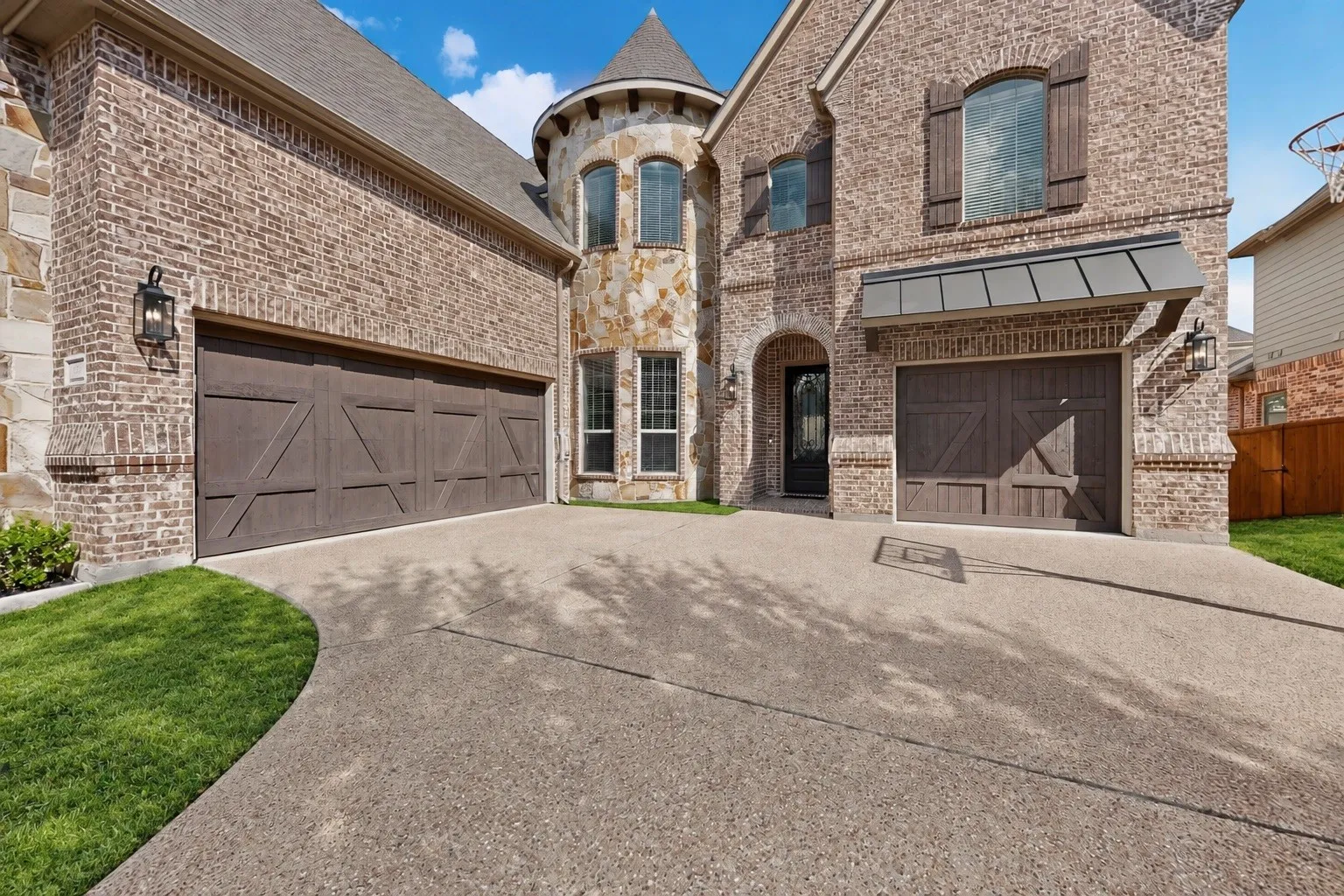 Brick and stone exterior featuring multiple garages, a turret, and decorative window shutters