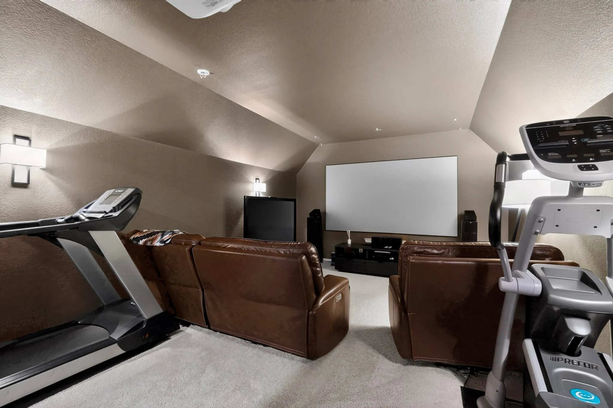Spacious room featuring sloped ceilings, recessed lighting, and wall sconces