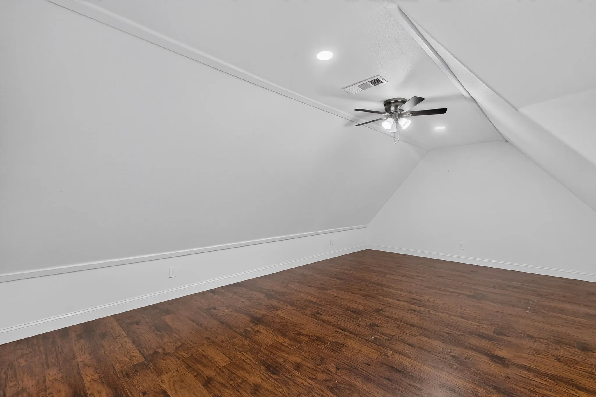 Attic space featuring wood-finish flooring, a ceiling fan, and recessed lighting