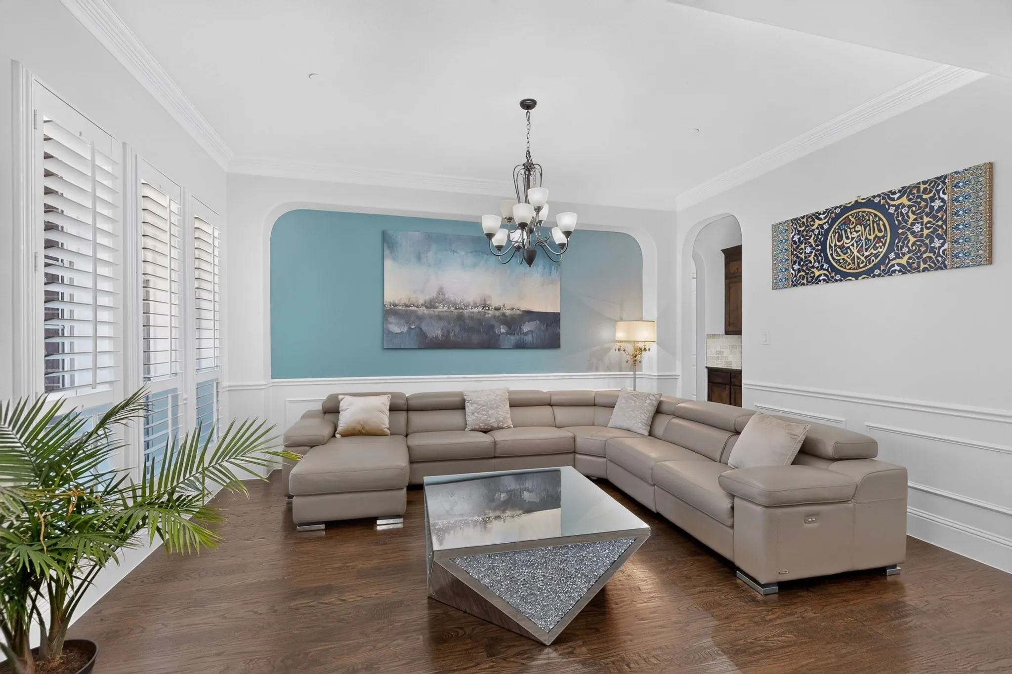 Living area featuring rich wood-finish flooring, white plantation shutters, and crown molding