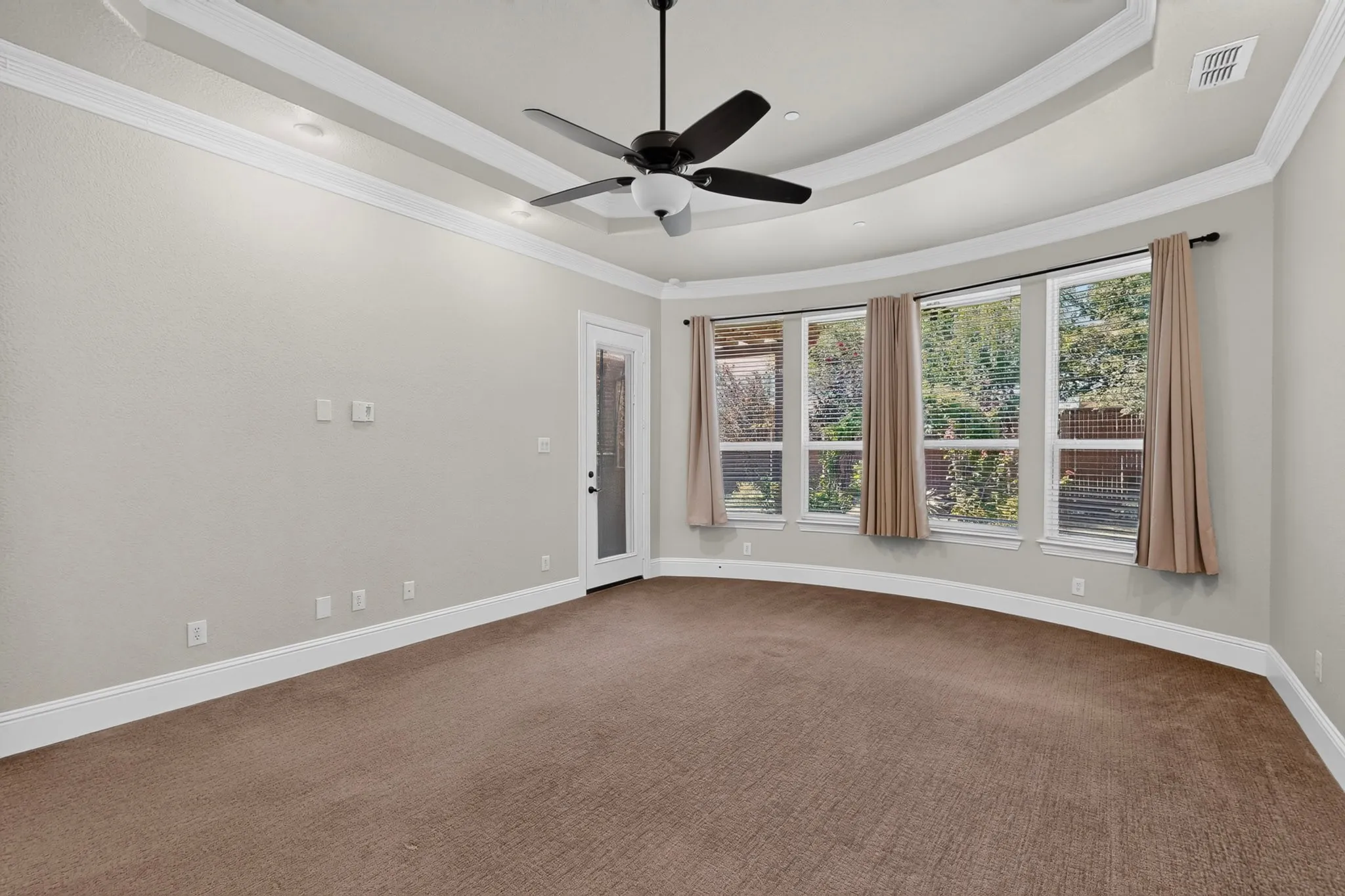 Spacious room featuring a tray ceiling with recessed lighting, crown molding, and a ceiling fan