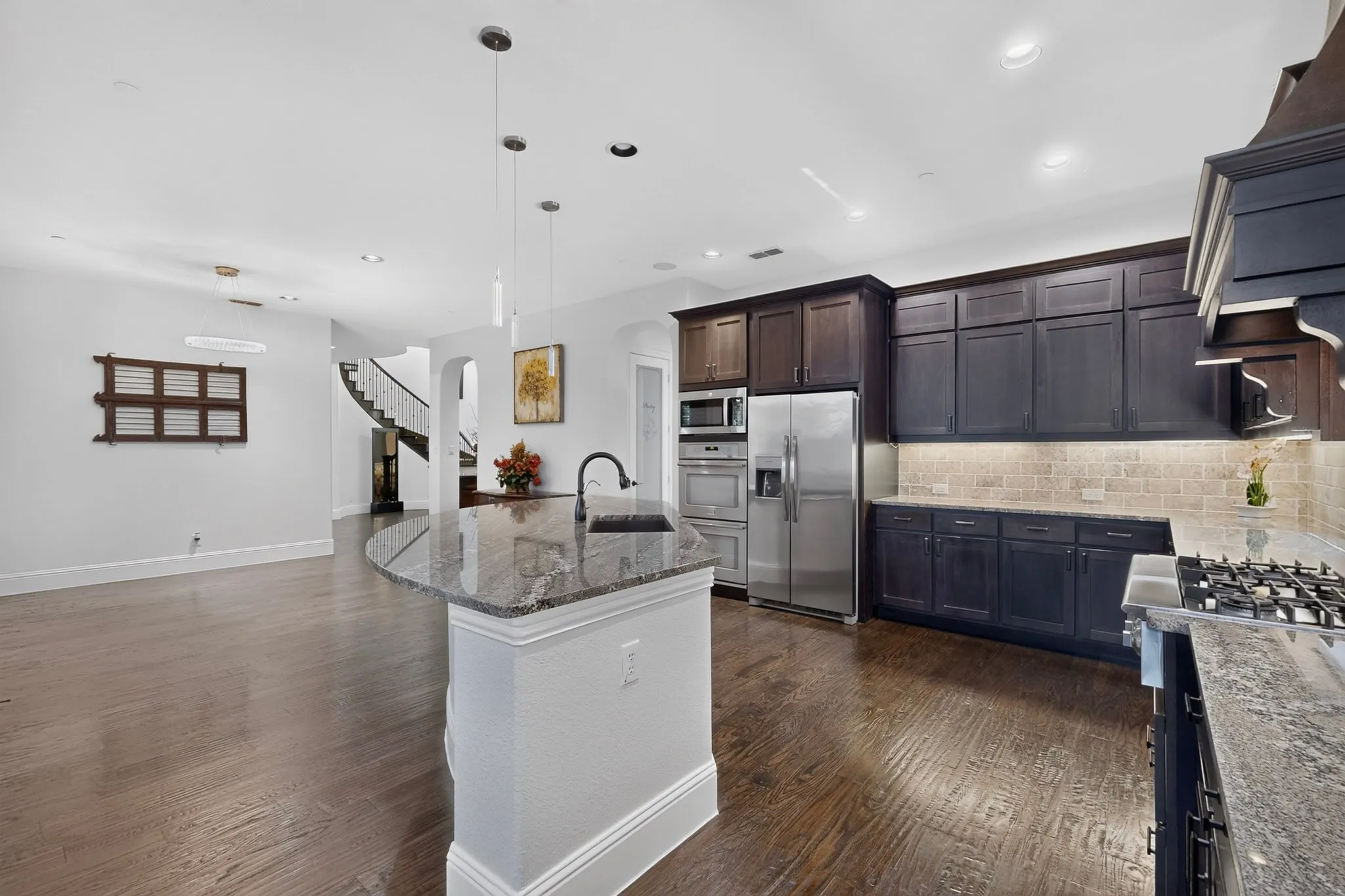 Gourmet kitchen with dark wood cabinetry, stainless steel appliances, a gas range, and granite countertops