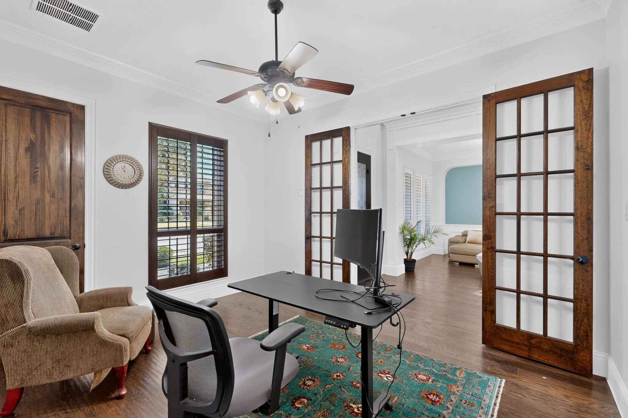 Room featuring a ceiling fan with integrated lighting, wood-finish flooring, and white crown molding