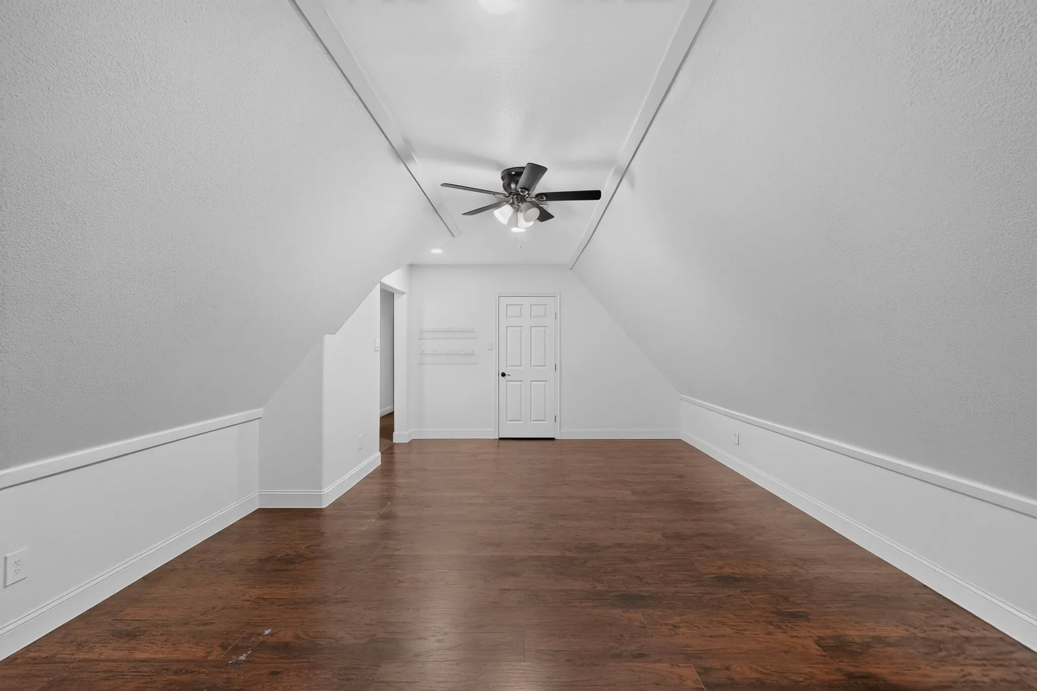 Spacious bonus room featuring wood-finish flooring, vaulted ceilings, and a ceiling fan with integrated lighting