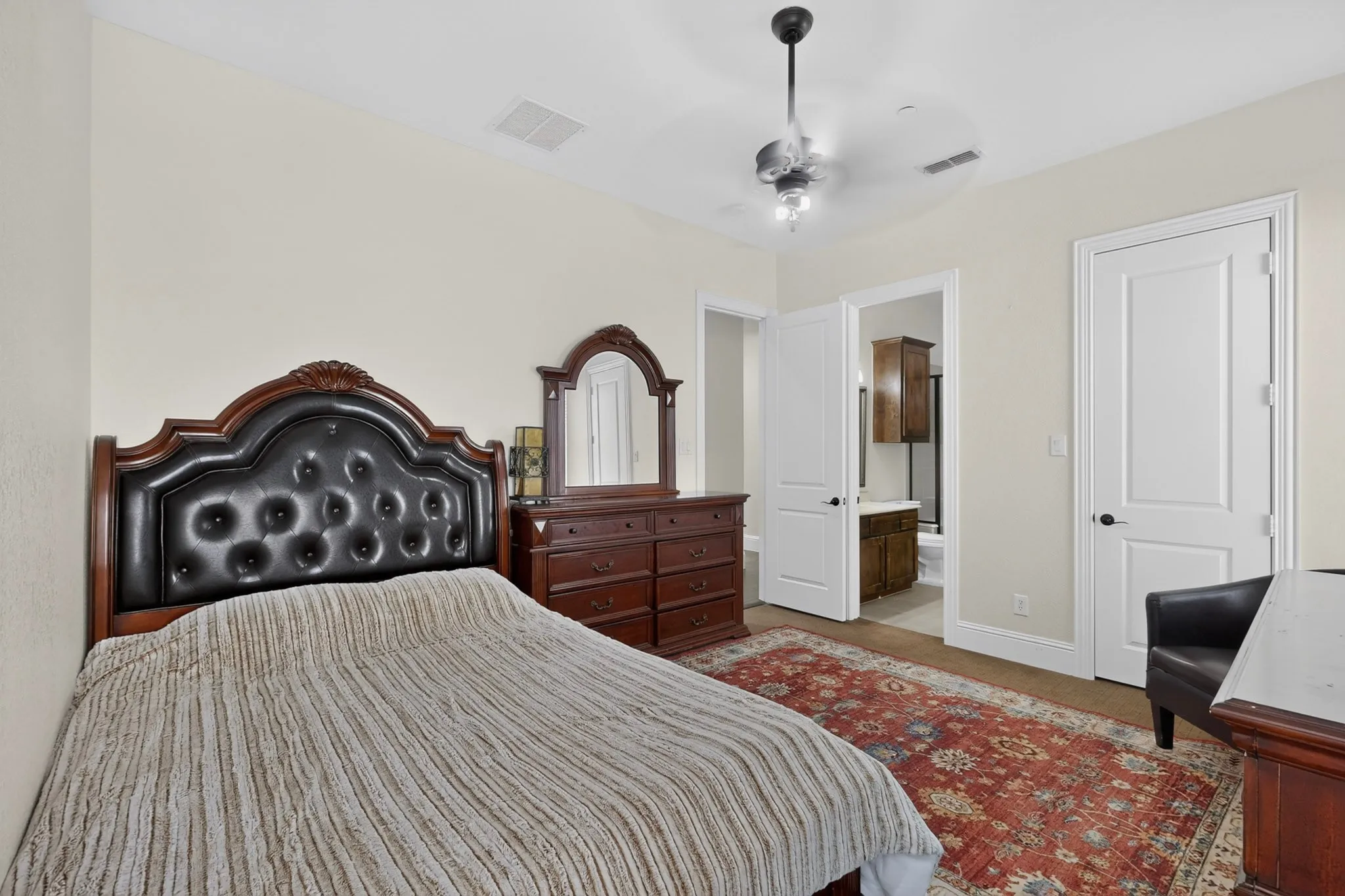 Carpeted bedroom featuring neutral-toned walls, a ceiling fan with integrated lighting, and a white paneled door