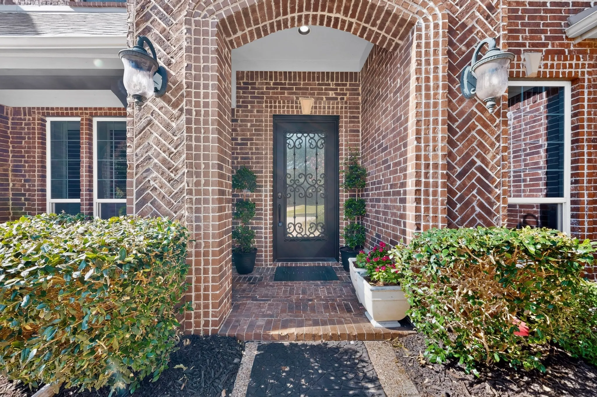 Brick exterior featuring a recessed entry, an arched doorway, and a wrought iron front door