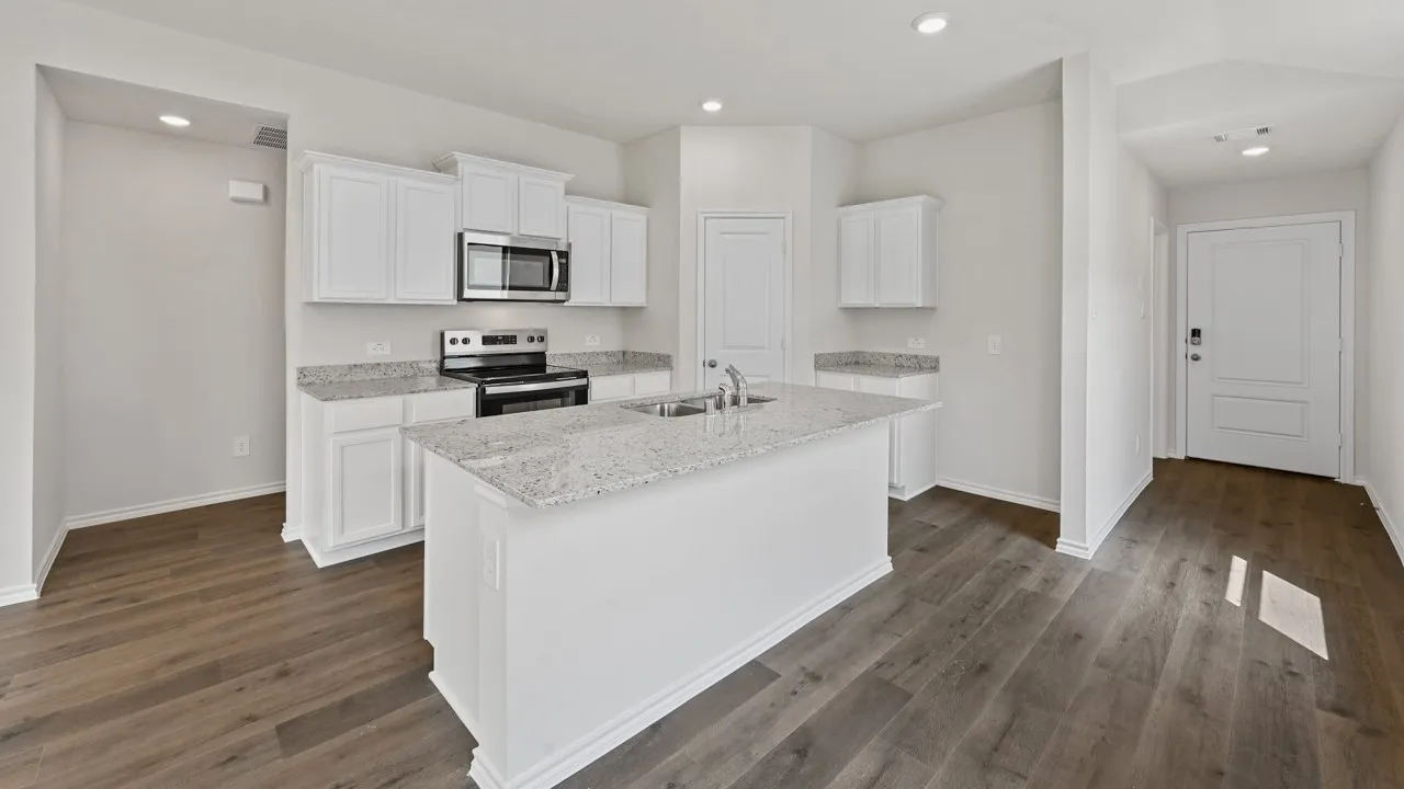 Kitchen featuring a central island with an undermount sink, granite countertops, white cabinetry, stainless steel appliances, and wood-finish flooring