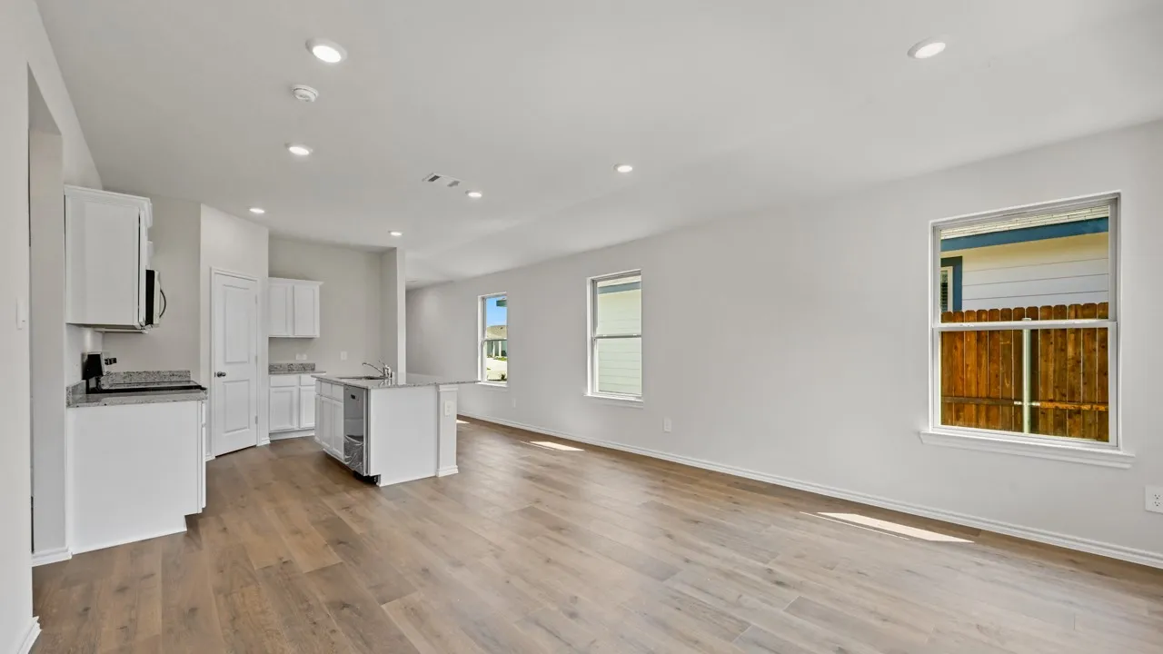 Open-concept living area featuring wood-finish flooring, recessed lighting, and multiple windows